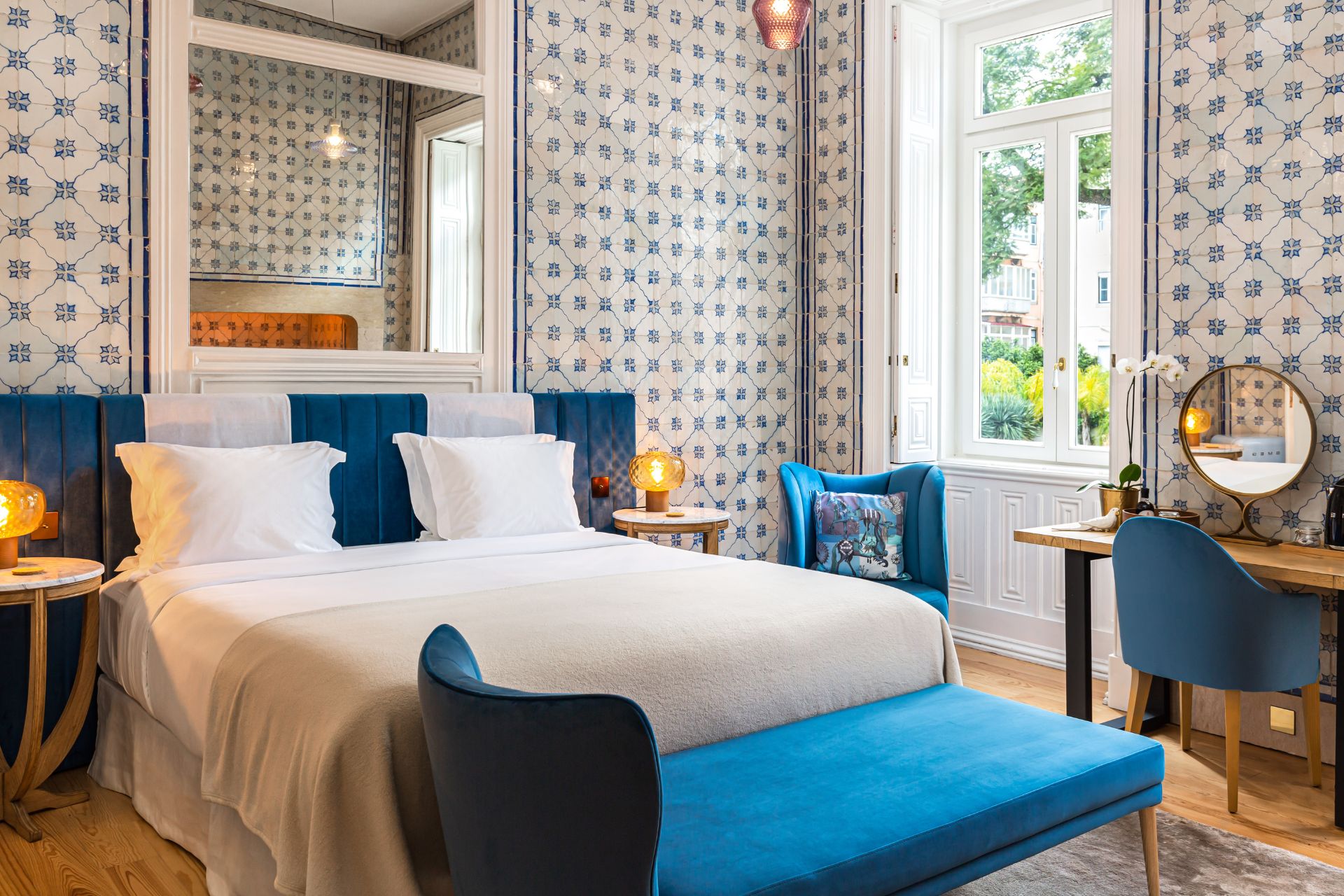 Bedroom with blue and white walls, white bedding, and a teal velvet chaise longue