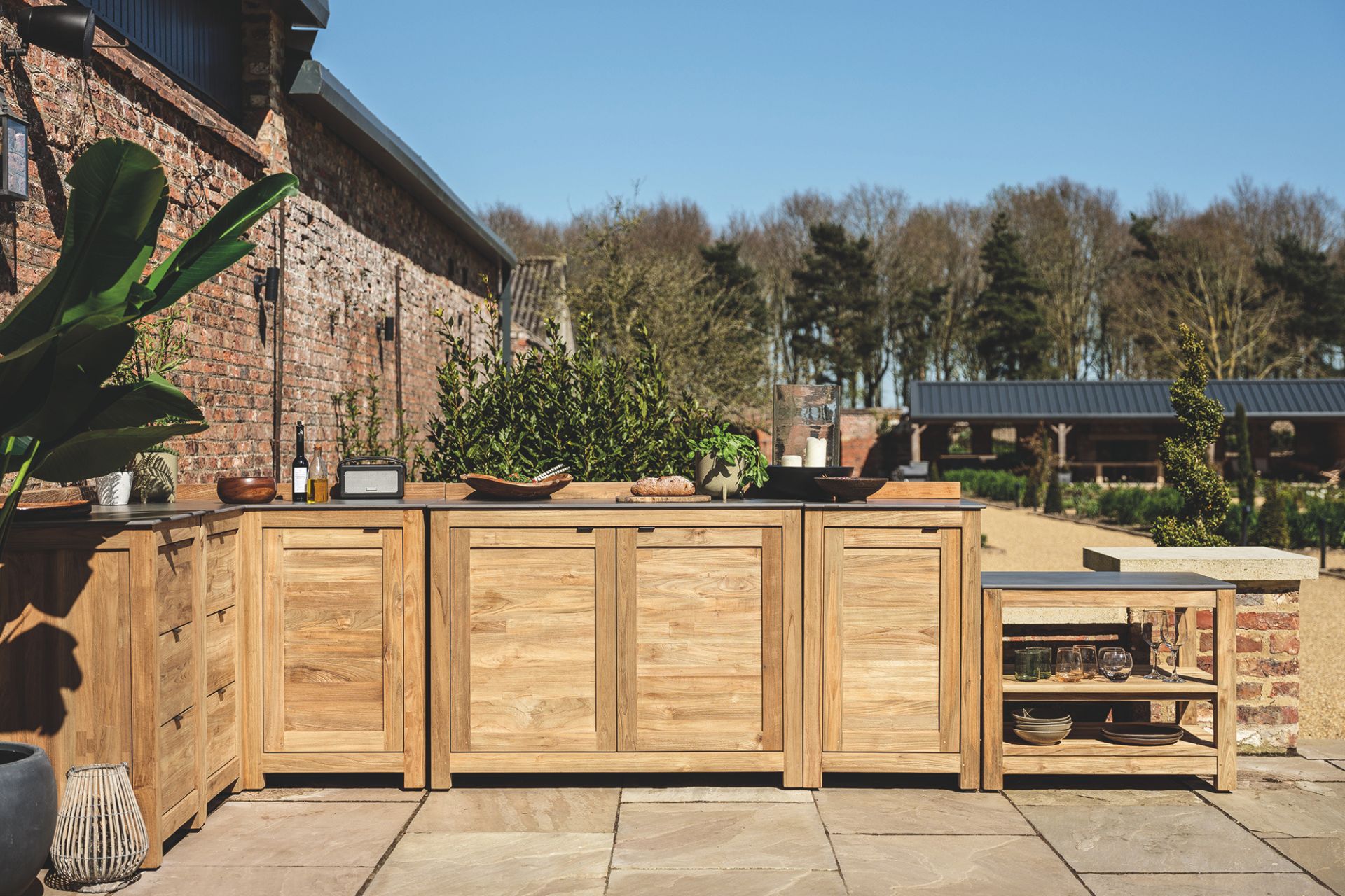 Outdoor kitchrn with pale wooden cabinets on a stone patio