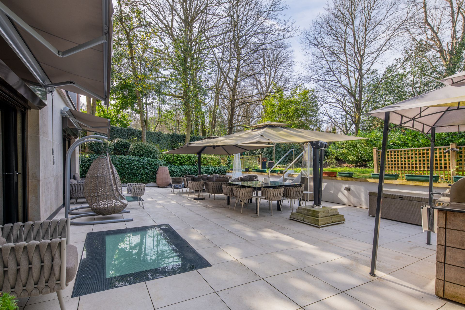 Garden with patio area, hanging chair, large dining set and outdoor kitchen.