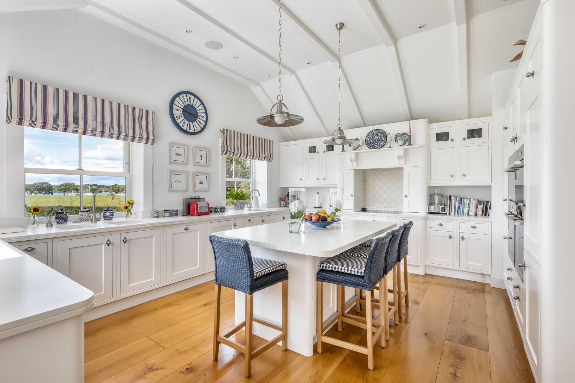 Coastal-style kitchen with wooden floors, white cabinets and a vaulted ceiling