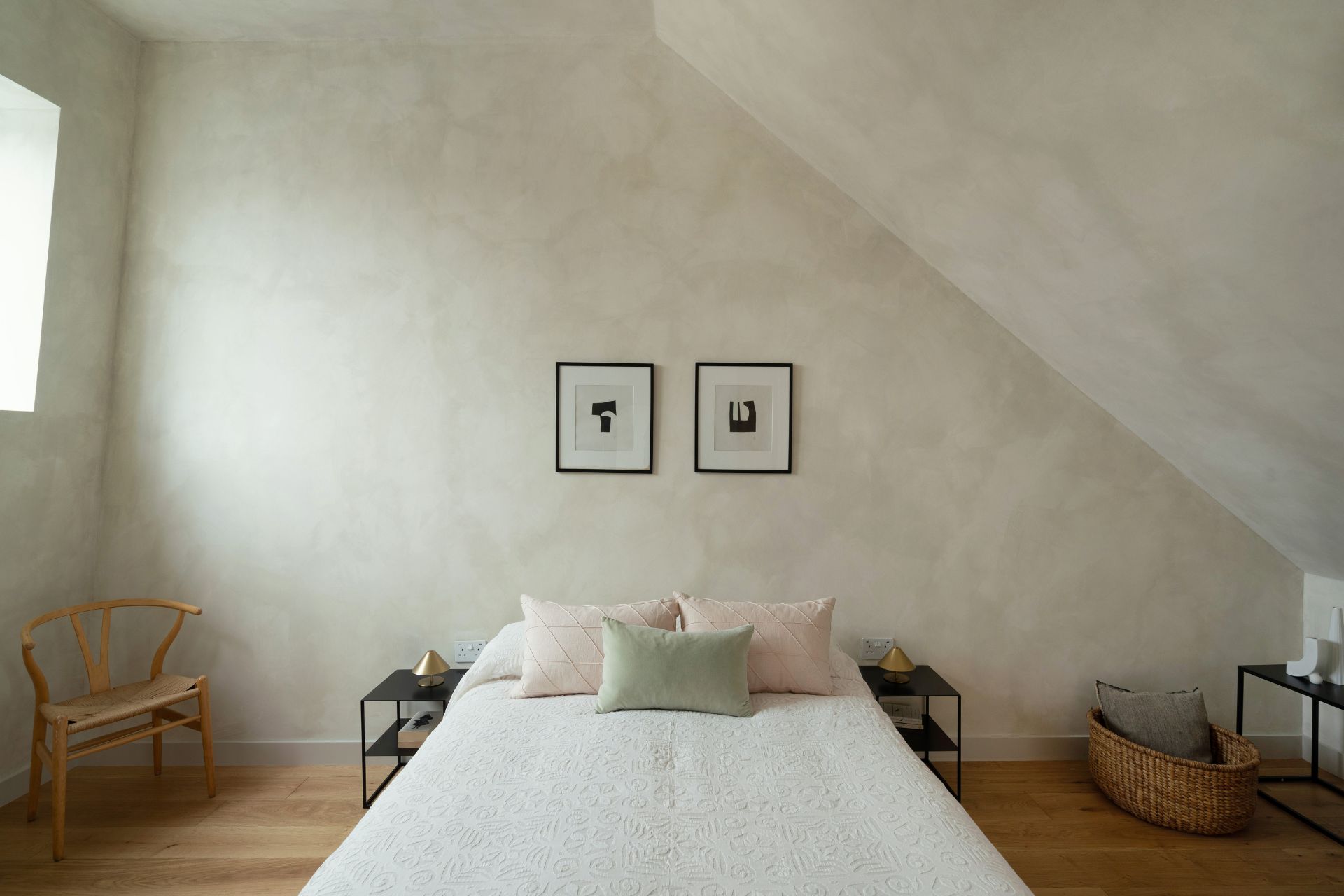 Attic bedroom with whitewash walls and pale pink and green cushions