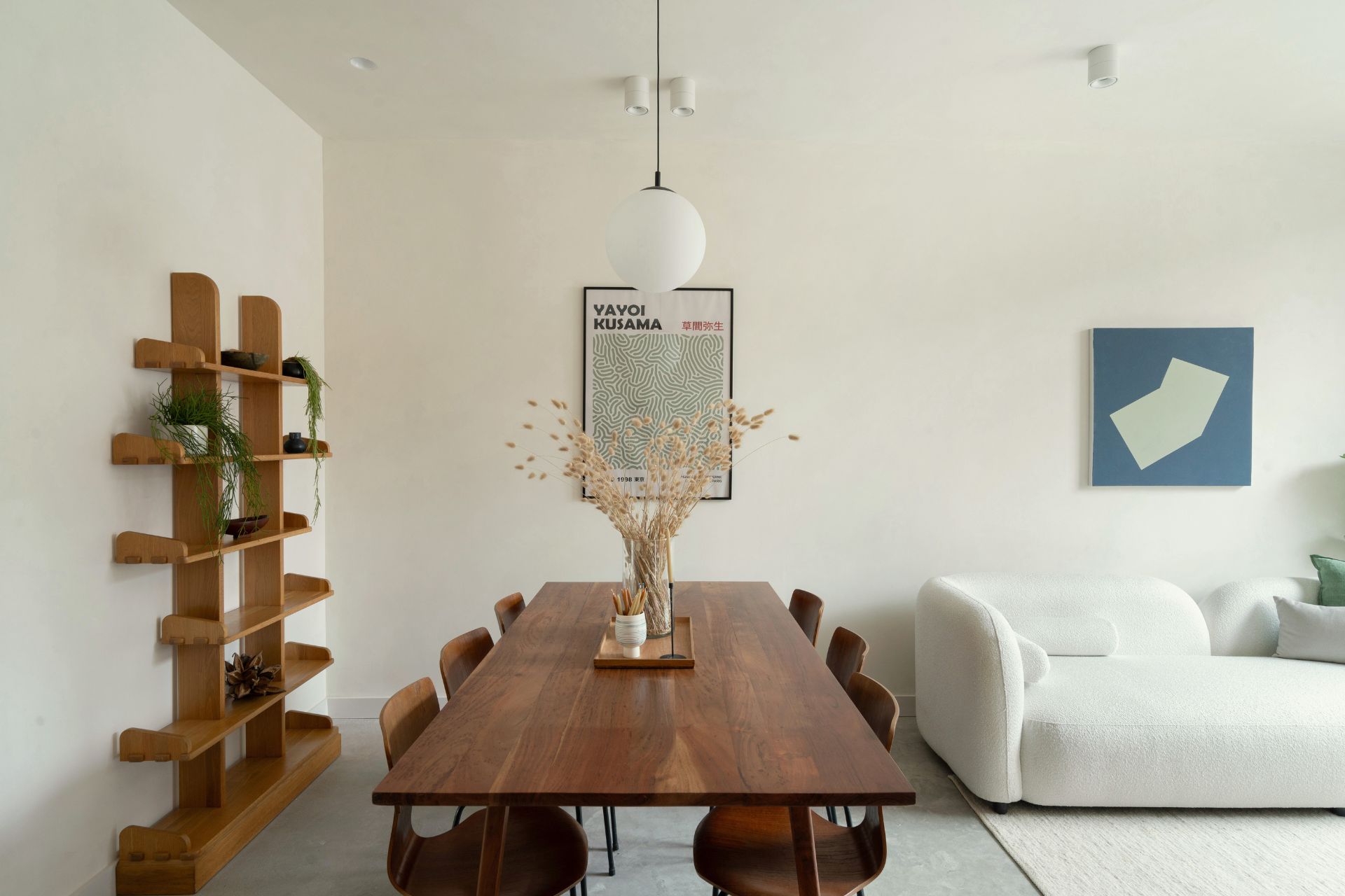 Dining room with rich wooden table, white lampshade and white boucle sofa