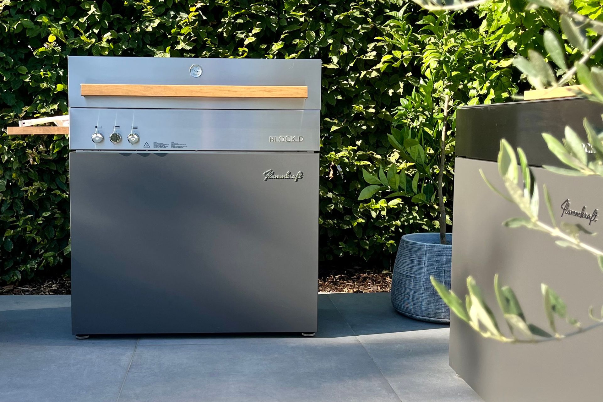 Garden with stainless steel grill and sage green outdoor kitchen cabinet