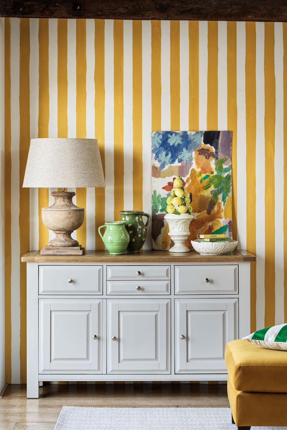Hallway with yellow and white striped wallpaper and a white sideboard