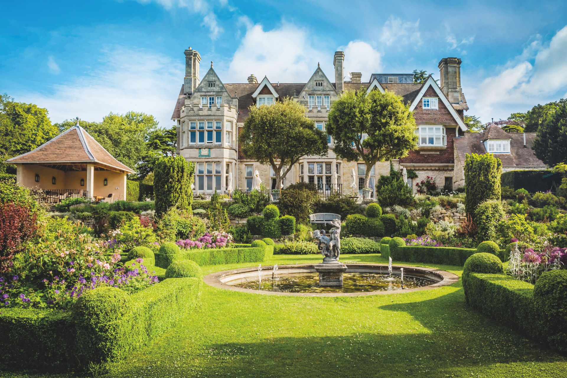 Large country house hotel with circular fountain and manicured lawn