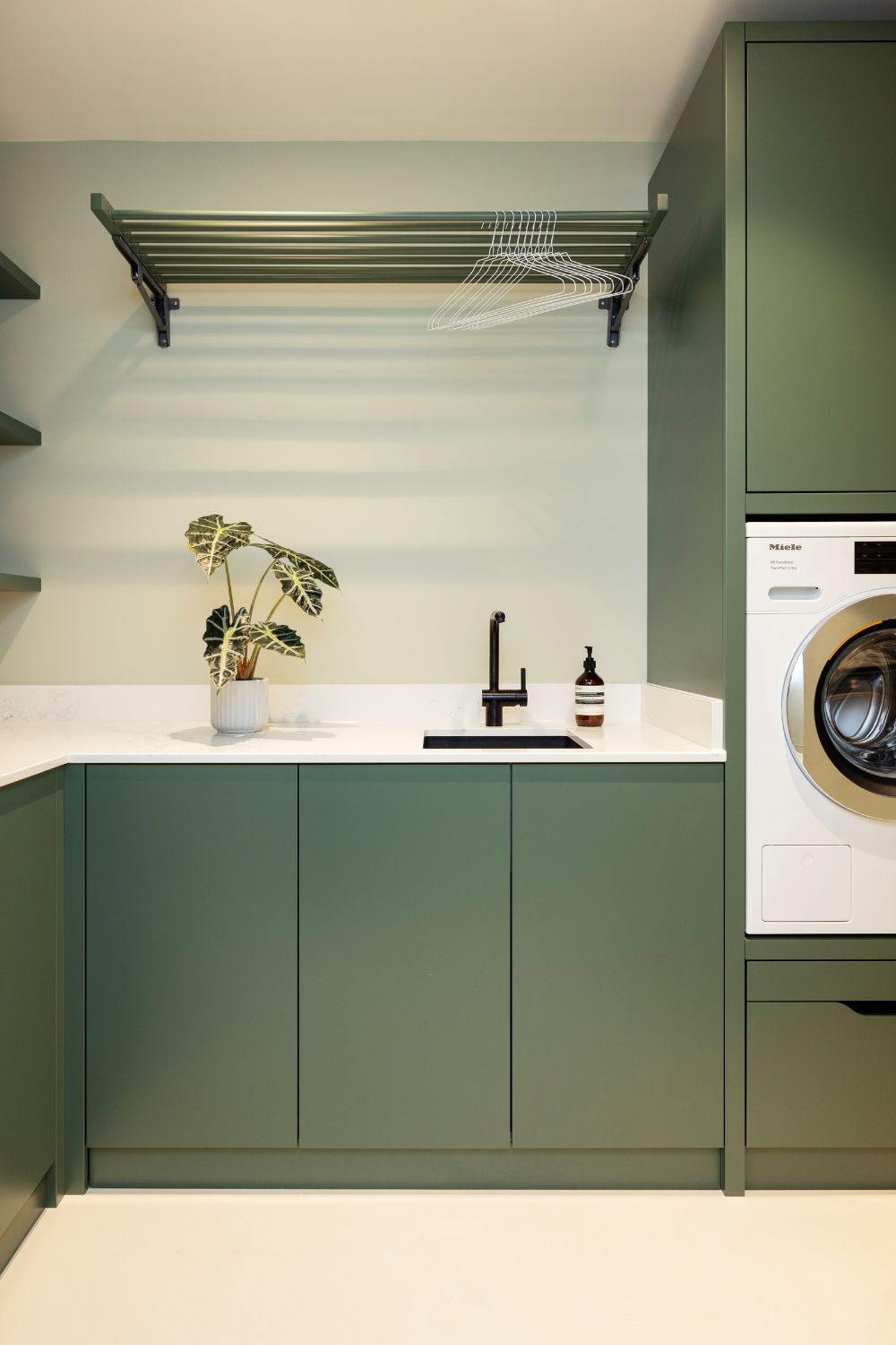 Utility room with olive green cabinets and white worktops