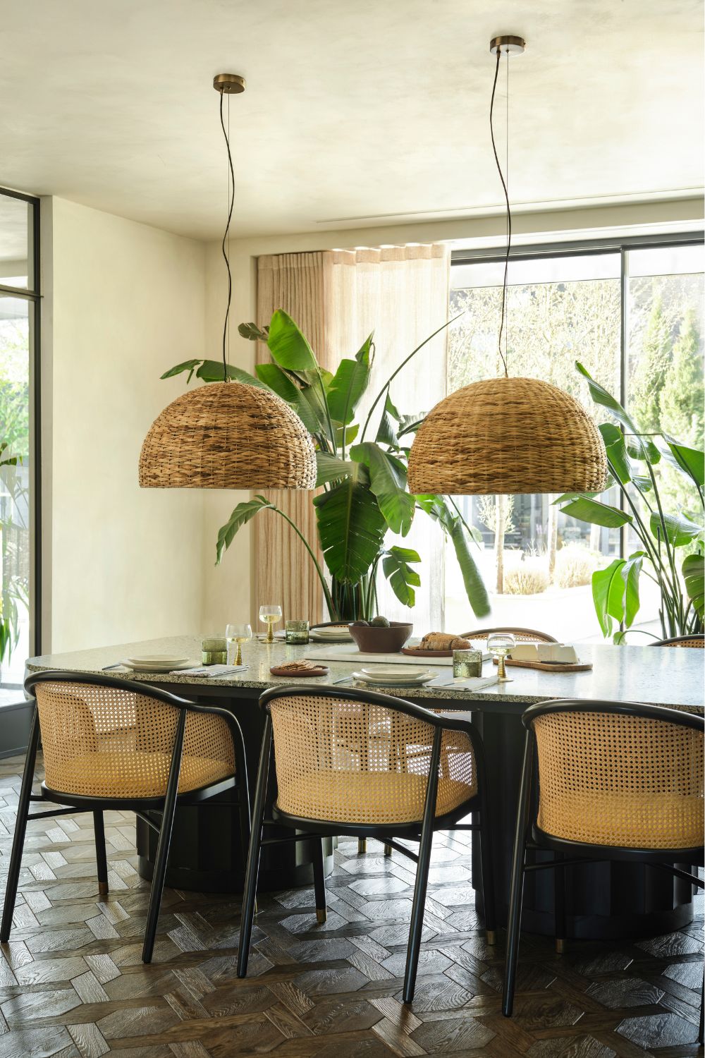 Dining table with rattan chairs, rattan pendant lights and large potted plants