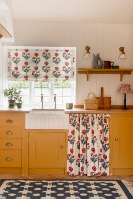 Utility room with mustard yelow cabinets and white floral curtains