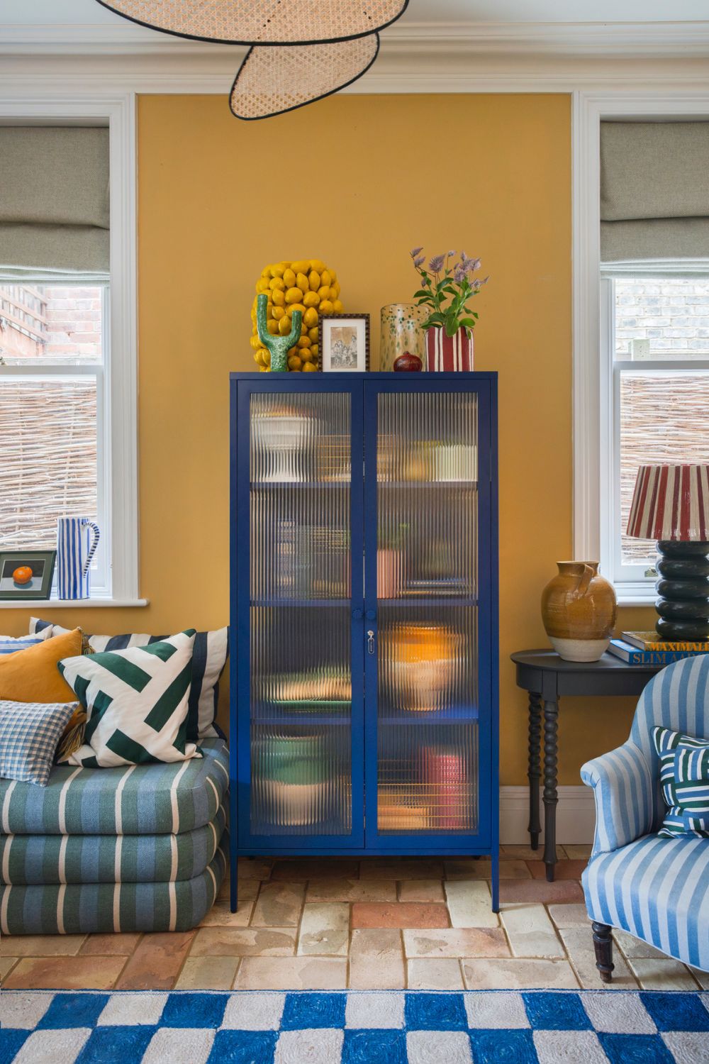 Deep yellow living room with navy shelves, blue striped seats and a blue and white checkerboard rug