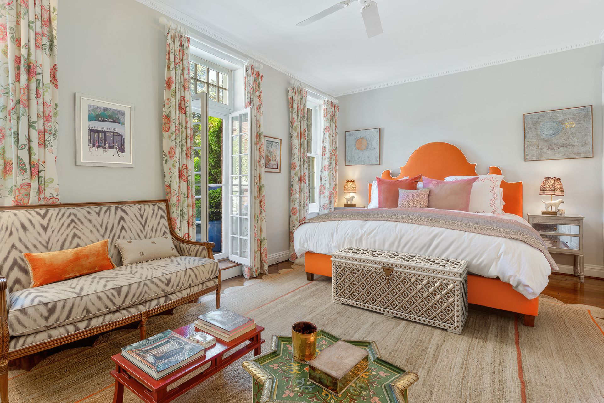 Bedroom with orange headboard, white bedding, floral curtains and a floral sofa