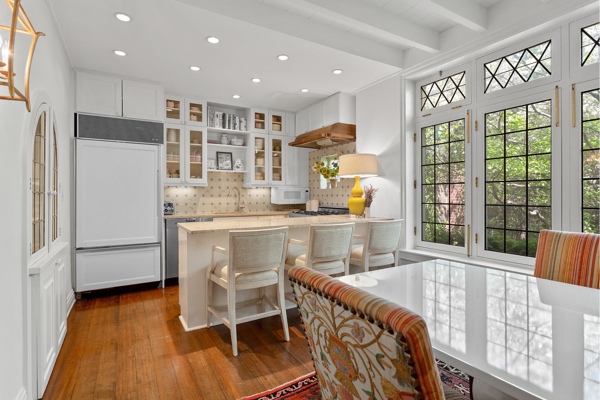 Farmhouse-style kitchrn with white units, a white breakfast bar, and a white dining table with patterned orange and white chairs