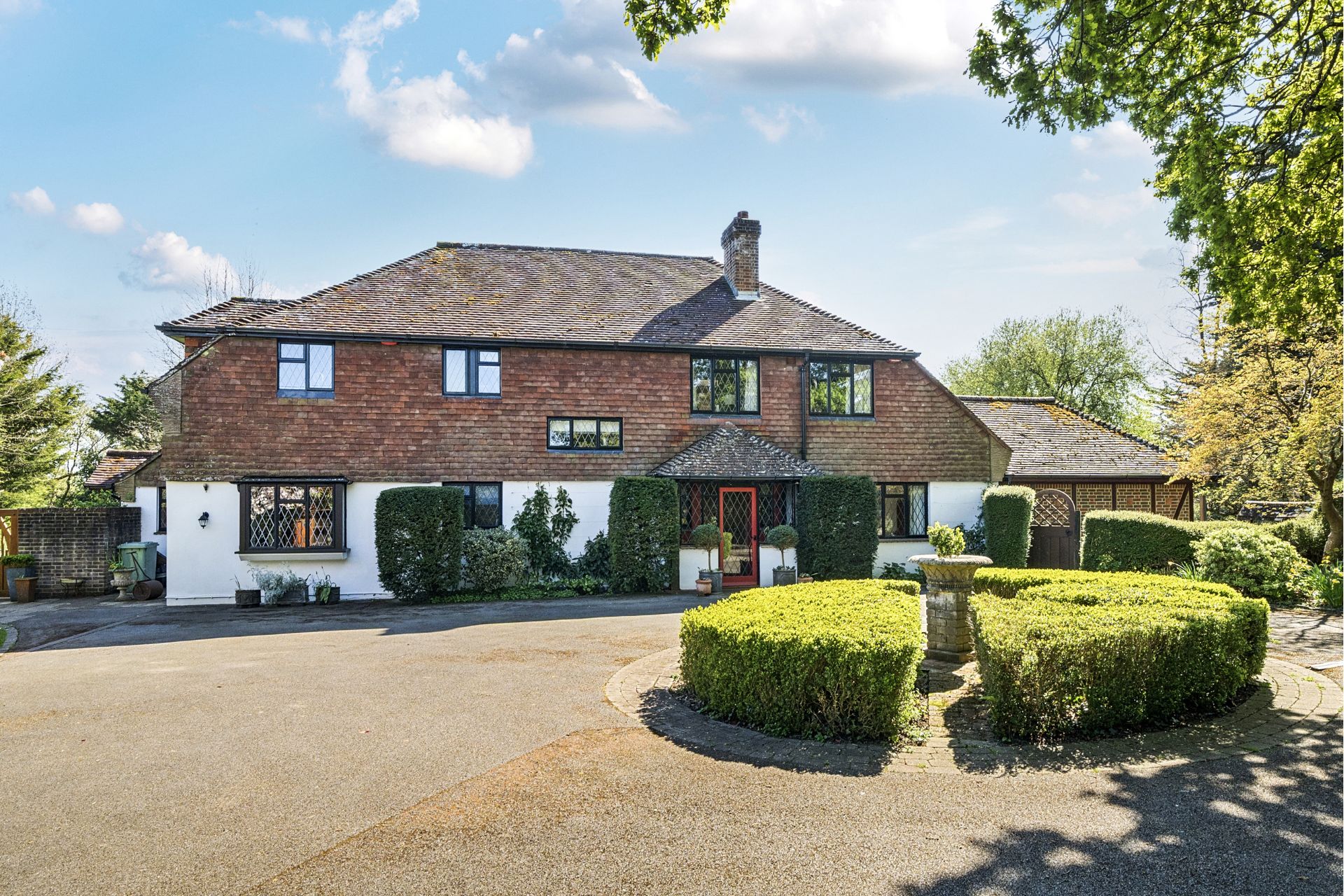 Red brick country home with carriage driveway and topiary hedges