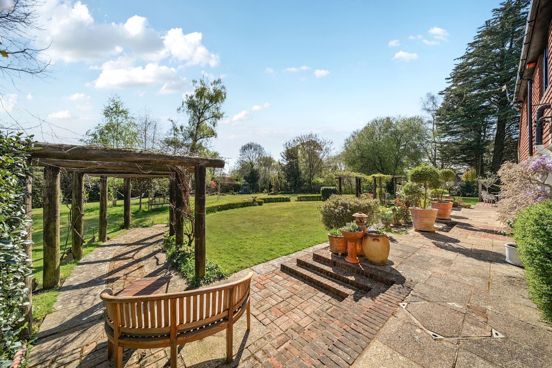Garden with stone terrace, seating areas, and landscaped lawn 