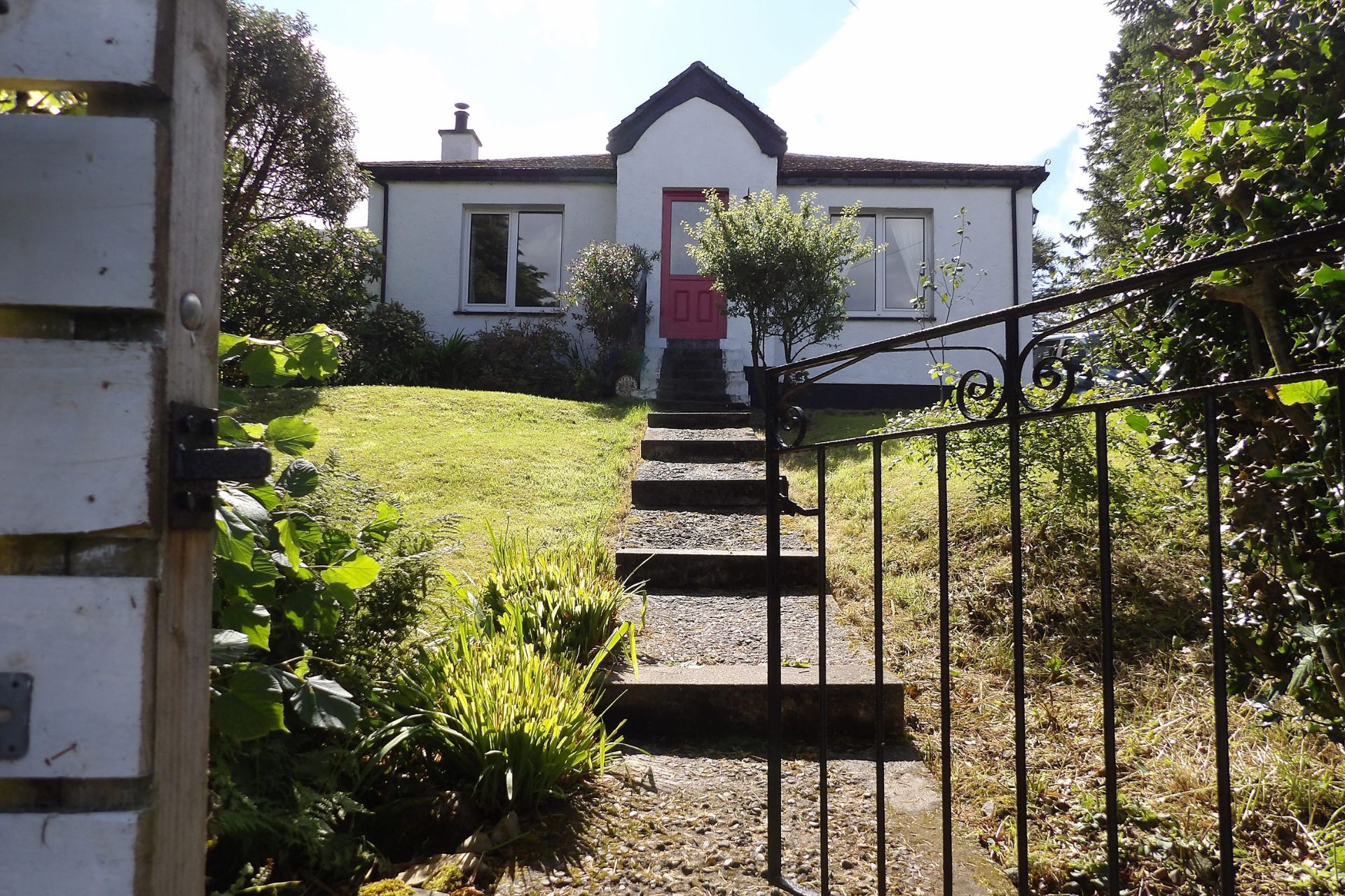 White bungalow with large lawn and stone steps