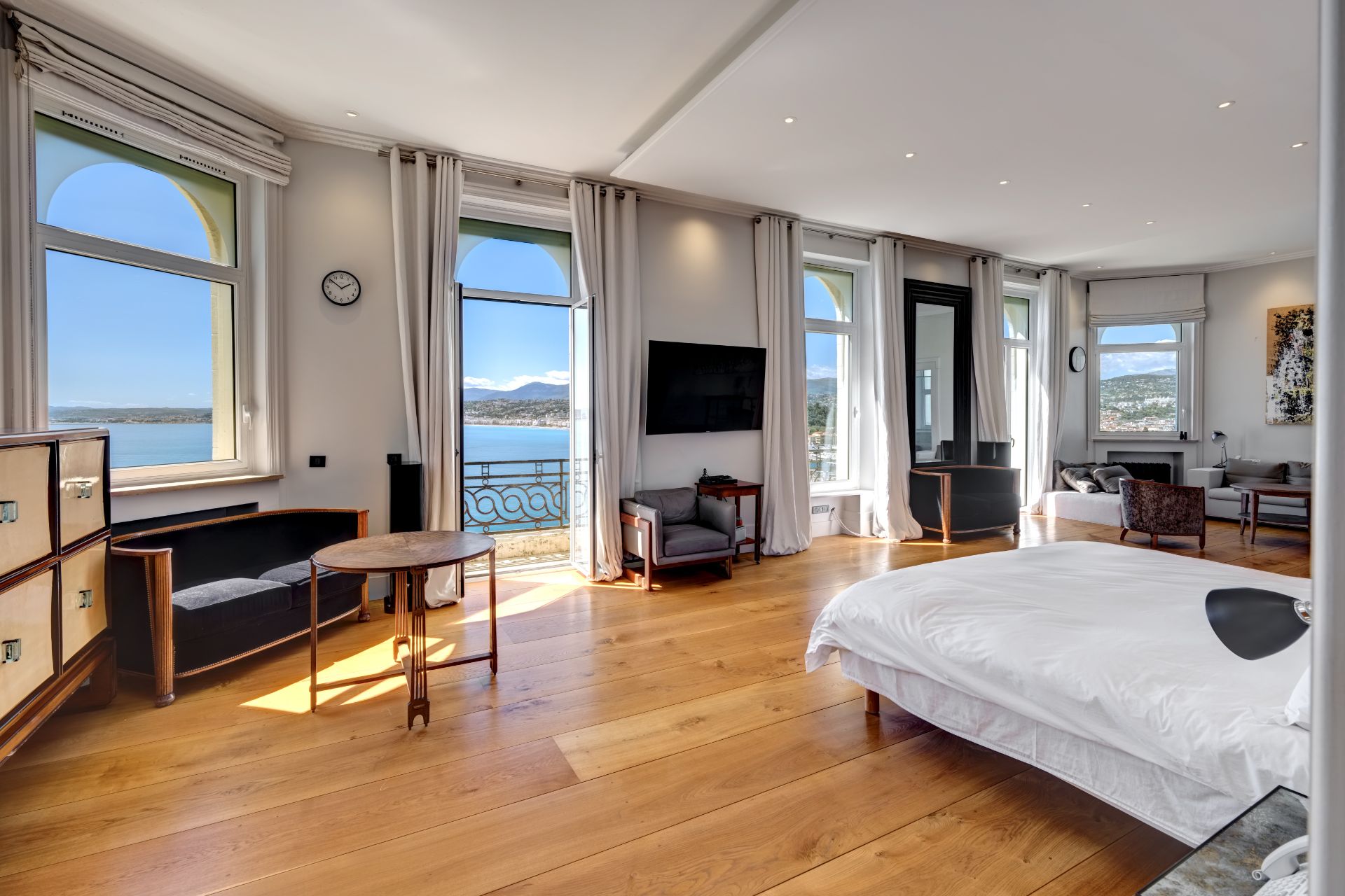 Bedroom with oak floors, large sash windows, and white bedding