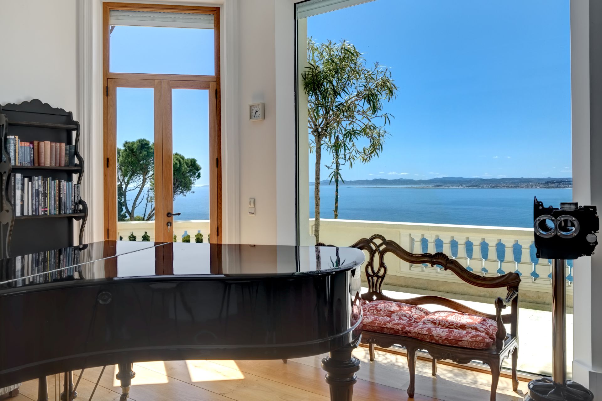 Living room with grand piano, Louis XVI-style chaise longue, and floor-to-ceiling windows overlooking the Port of Nice