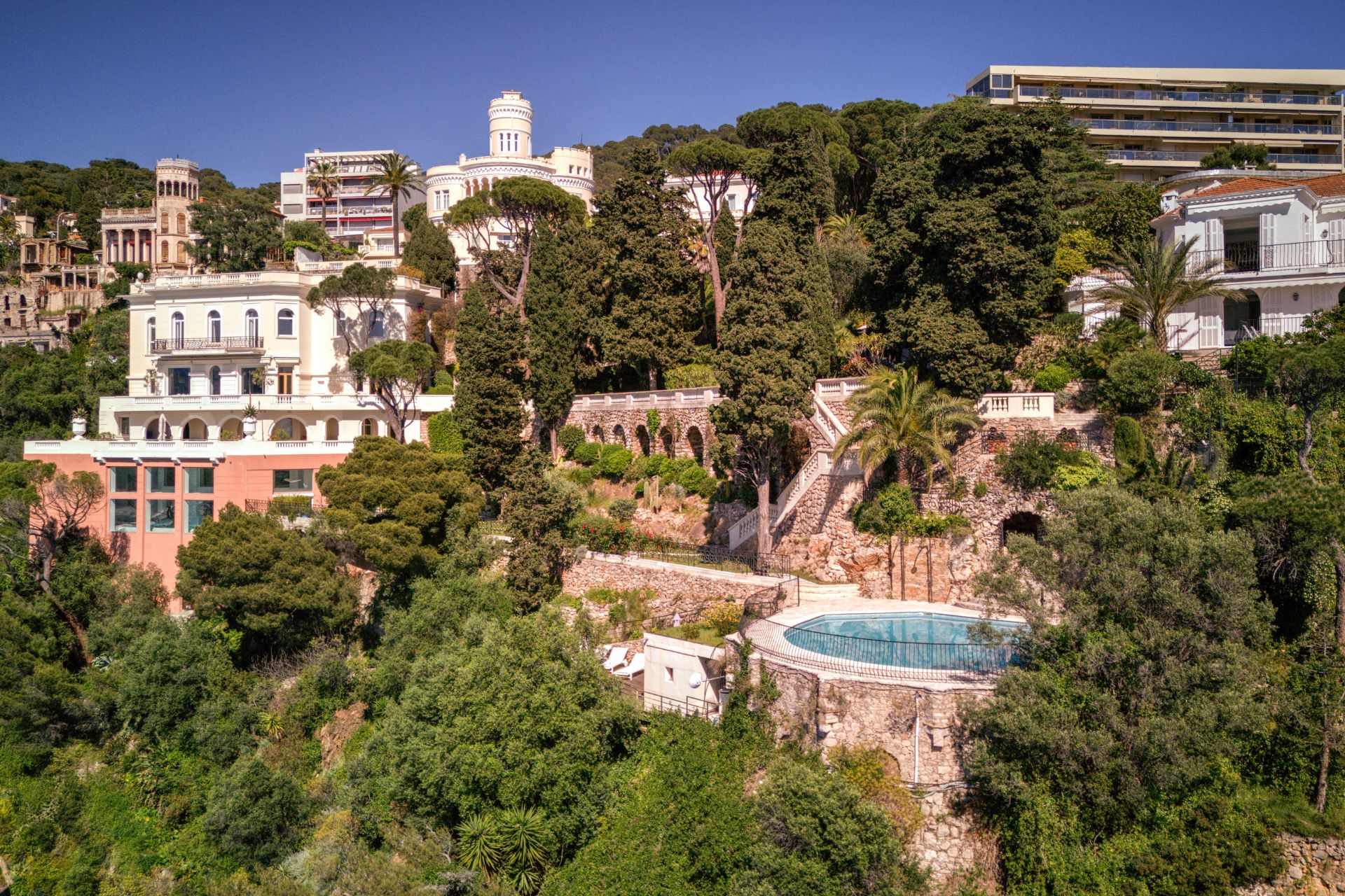 Aerial view of hillside Ar Deco villa on the French Riviera, with landscaped gardens and a circular swimming pool