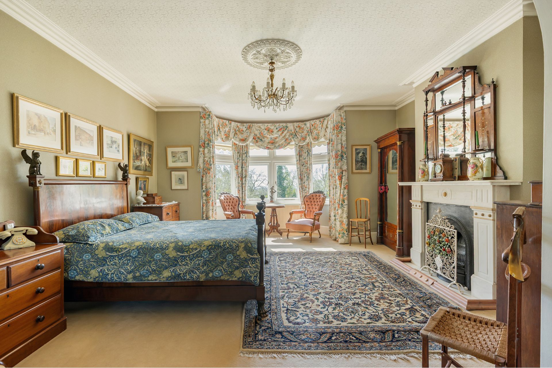 Bedroom with chandelier, bay window, and blue floral bedding