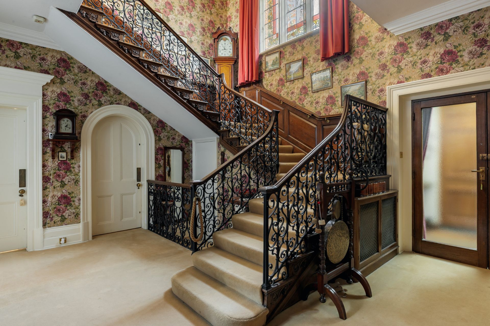 Hallway with ornate carved staircase and floral wallpaper