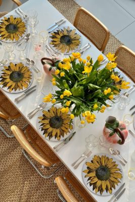 Aerial view of white table with yellow tulips and sunflower placemats.