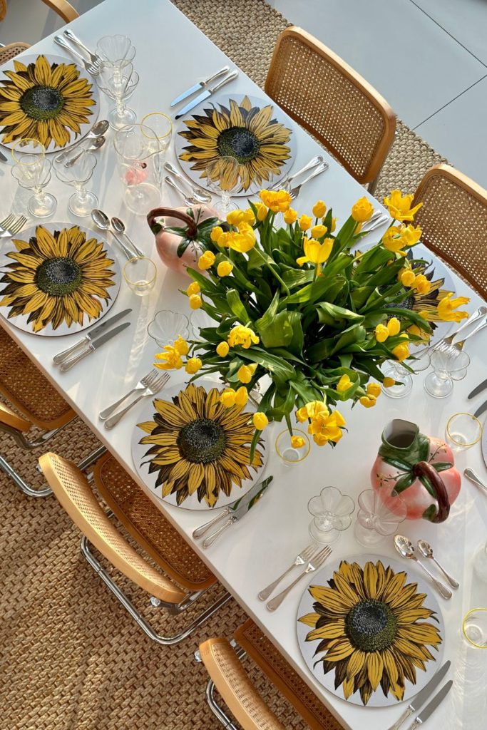 Aerial view of white table with yellow tulips and sunflower placemats.