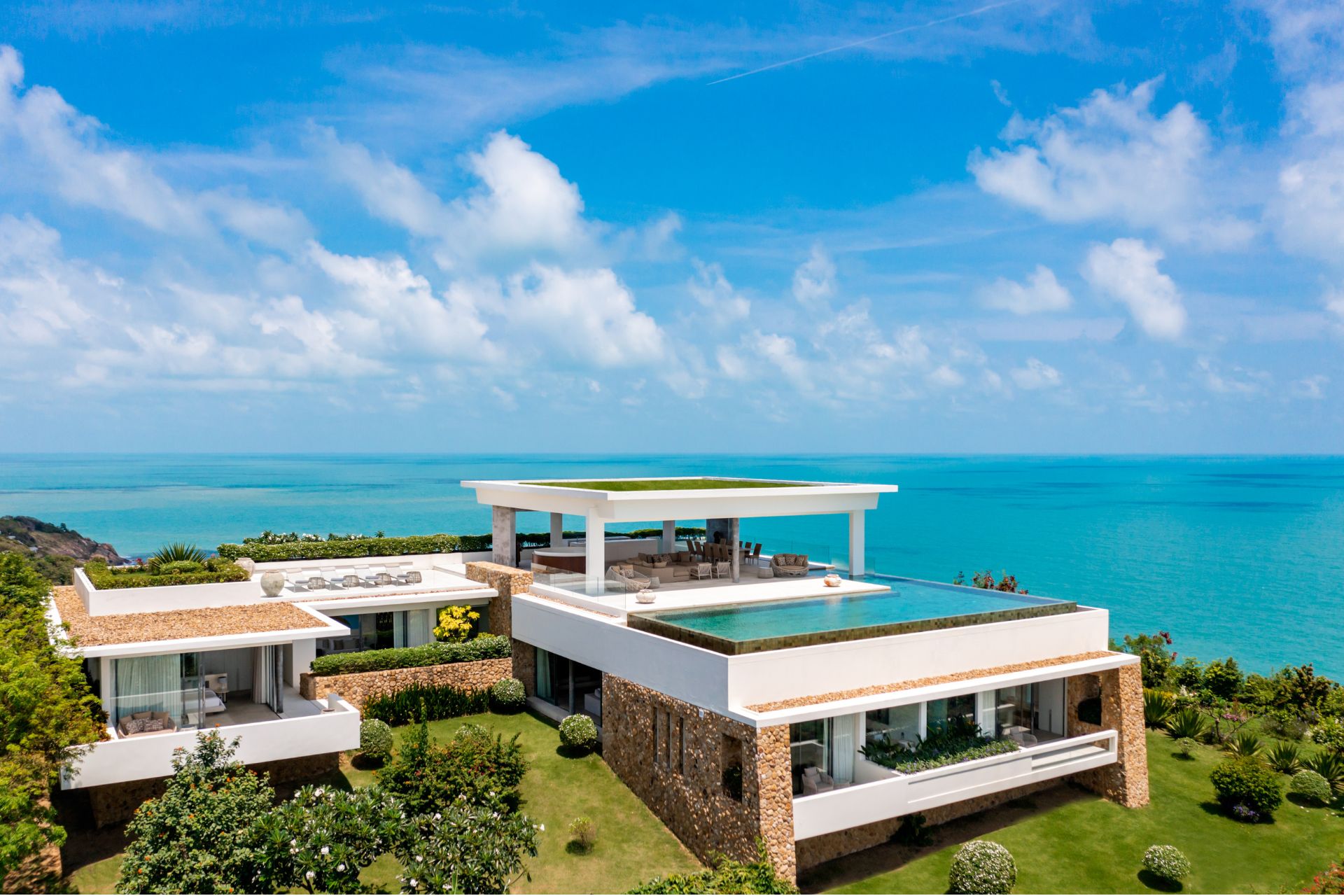 Arial view of modern villa with lawn, roof deck and infinity pool