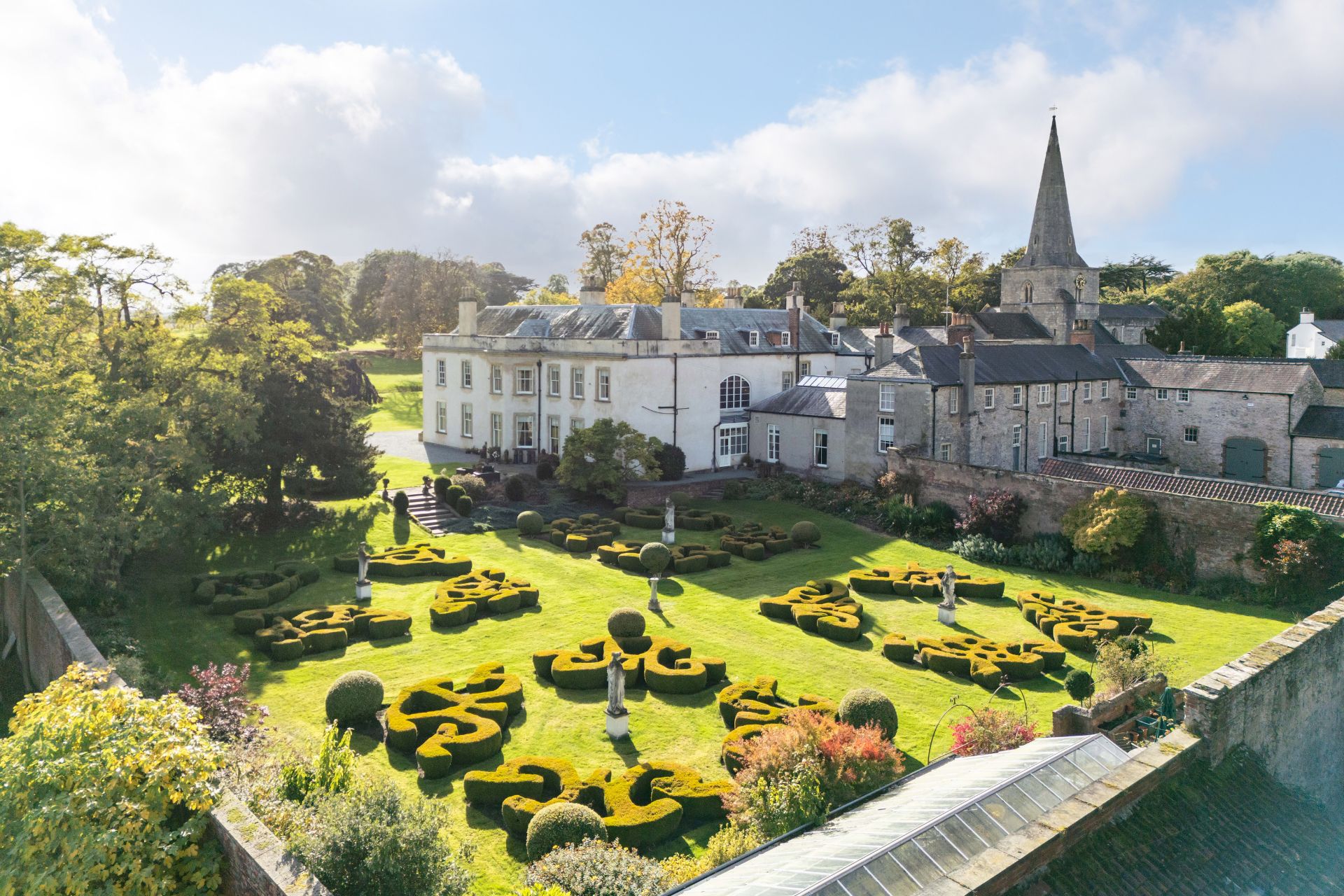 Aerial view of country home with landscaped hedges and a walled garden
