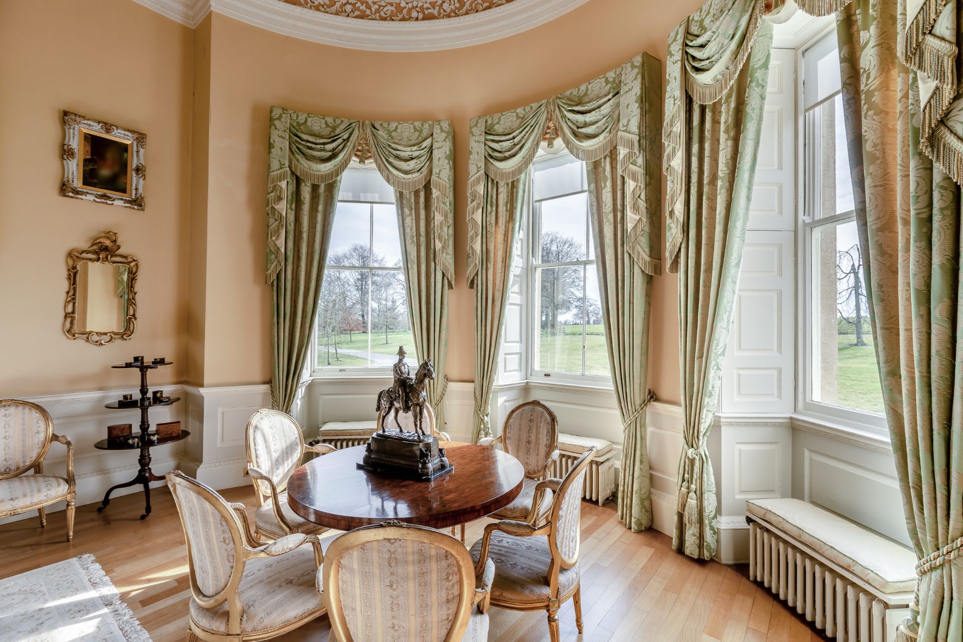 Stately honme dining room with circular mahogany table and cream chairs
