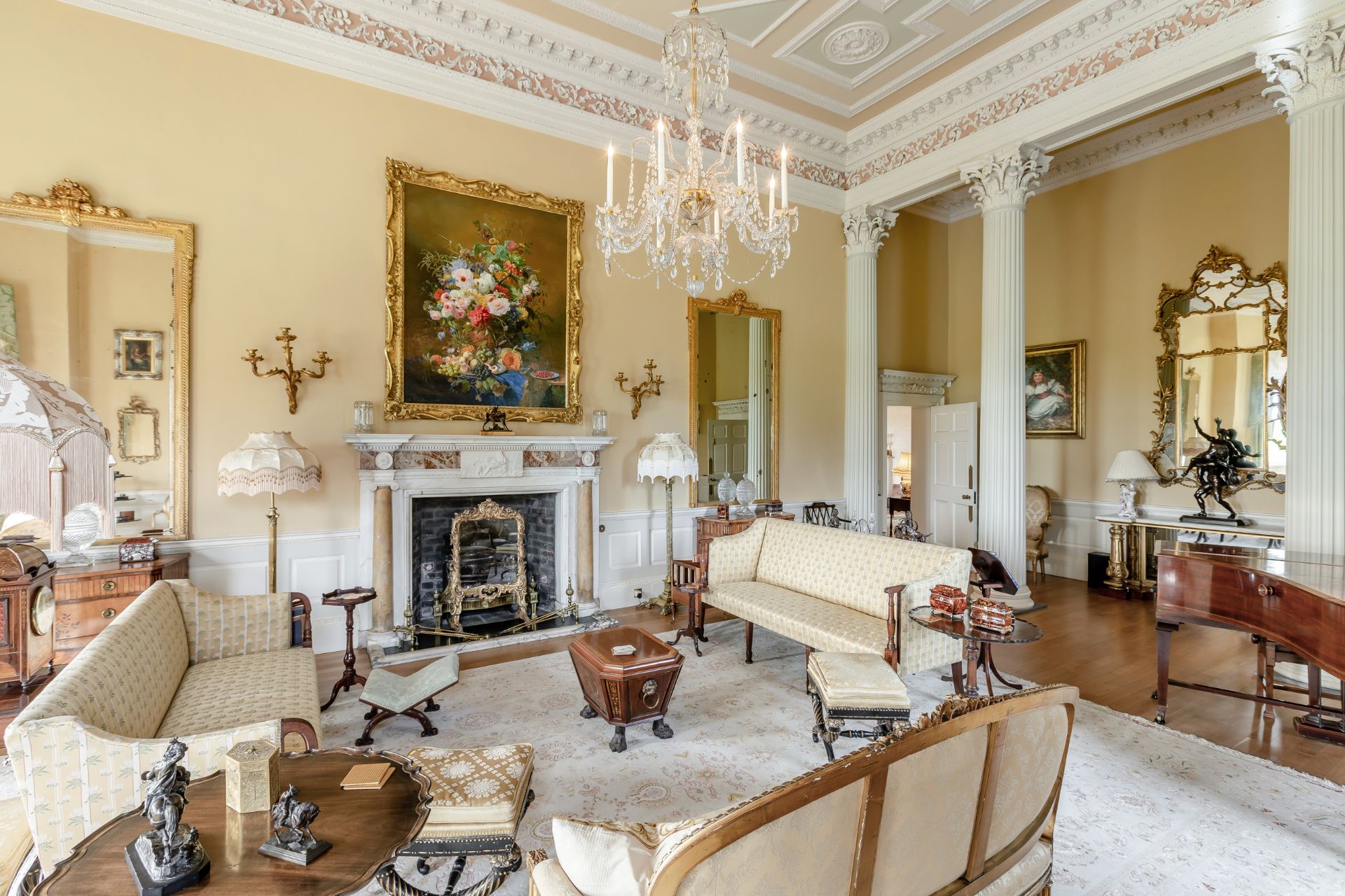 Stately home living room with marble fireplace, grand piano, and chandelier