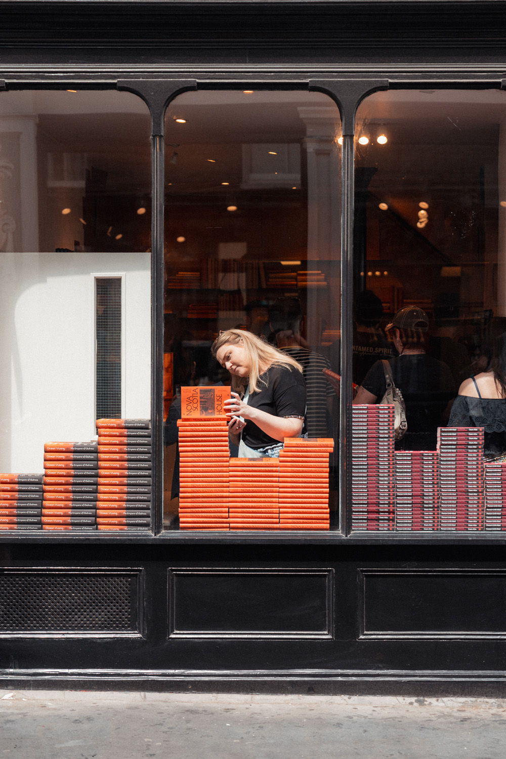 A woman looking at a stack of books in a shop window