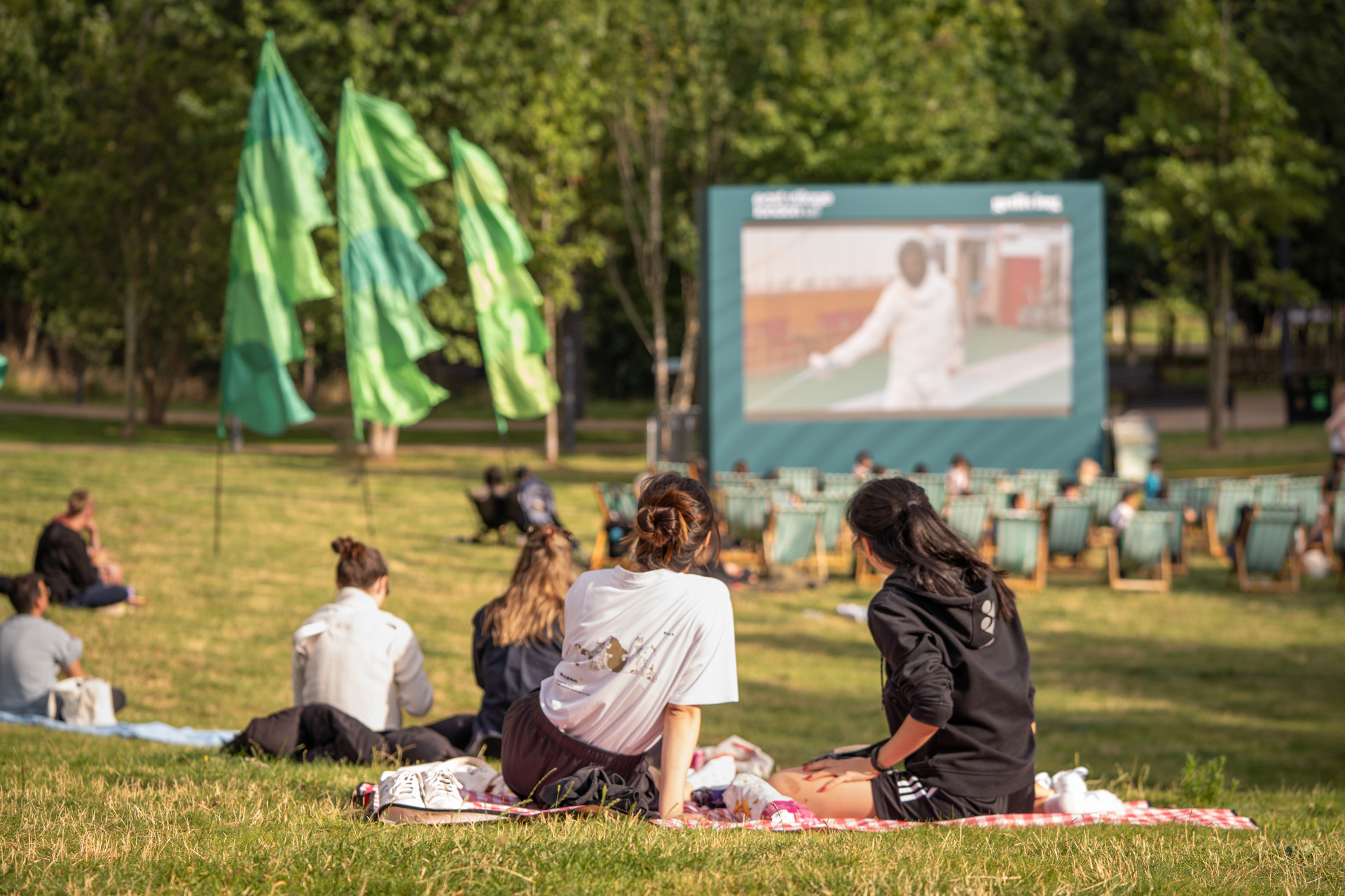 Londoners picnicking in front of a Wimbledon screen