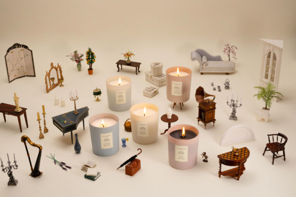 Collection of mood-paired candles by Jo Malone and Little Greene all laid out on a surface with tiny doll's house items