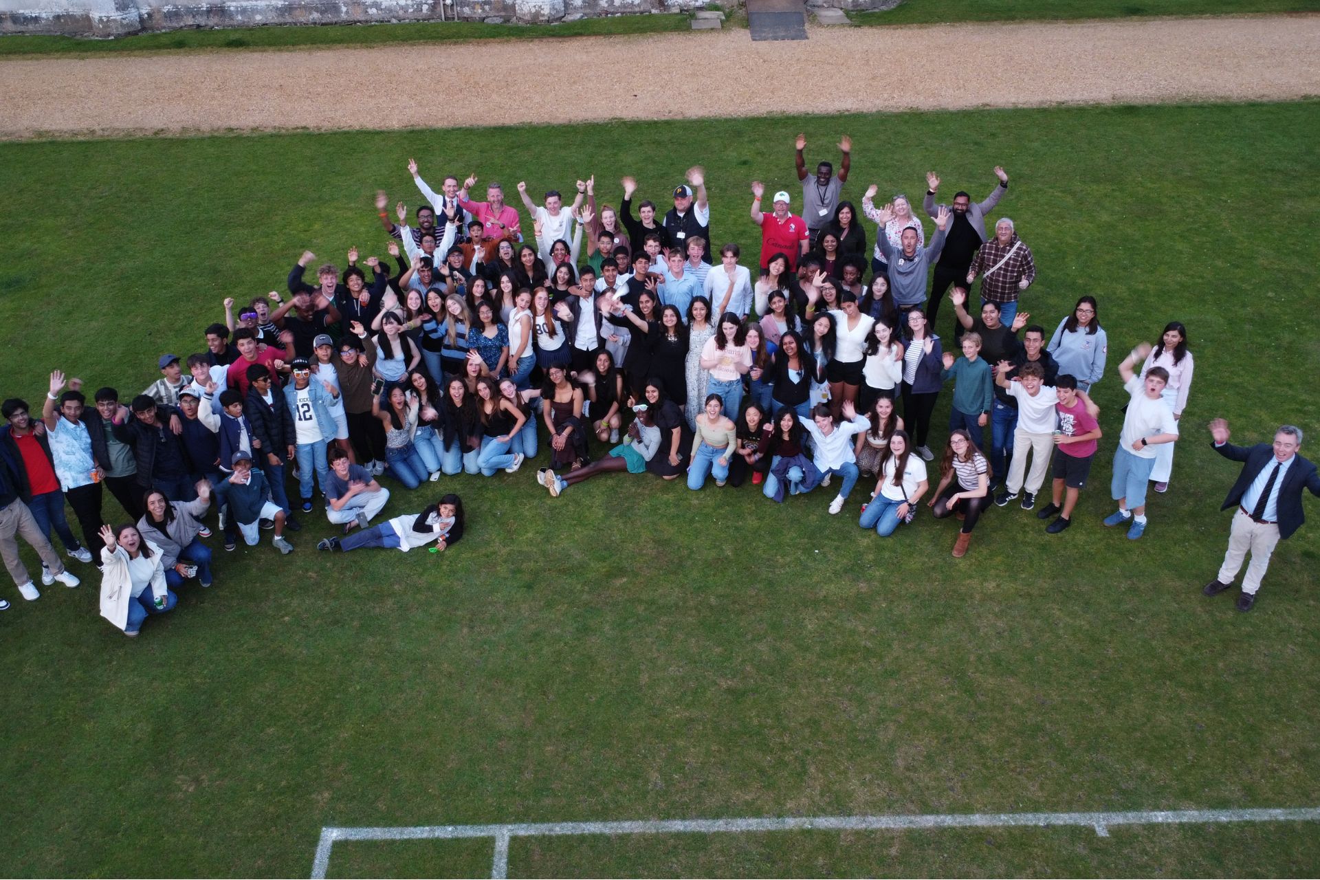 Aerial photo of a large group of children with their hands in the air
