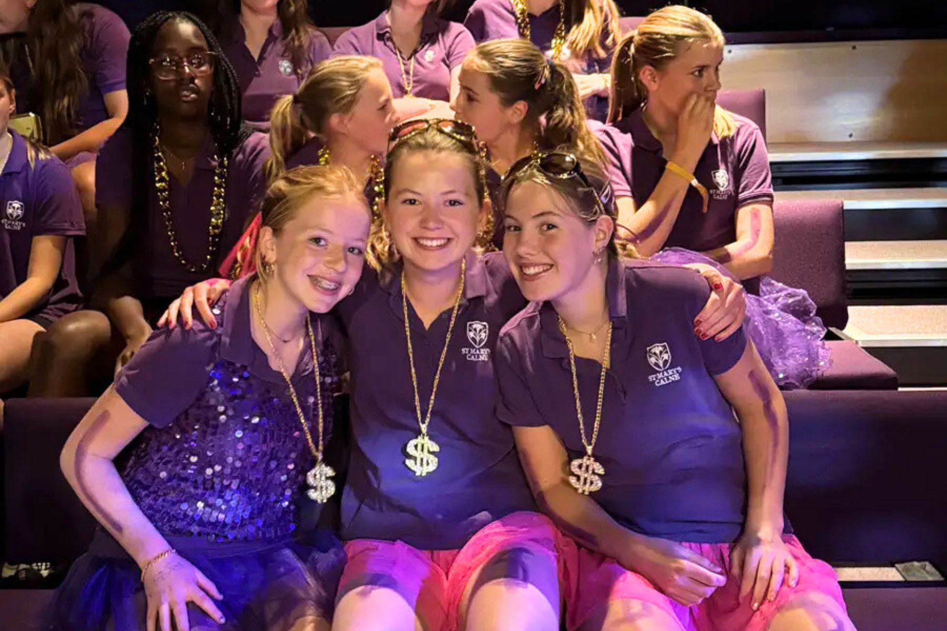 St Mary's Calne pupils wearing purple outfits and gold necklaces, posing for a picture at the event