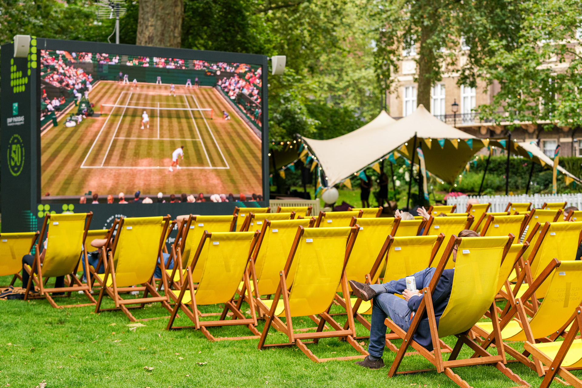 A large screen showing Wimbledon tennis