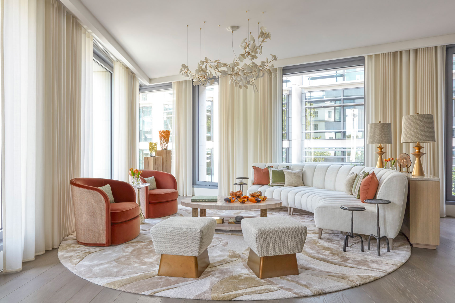 A cream and auburn themed living room. Decorative leaf chandelier. Curved sofa.