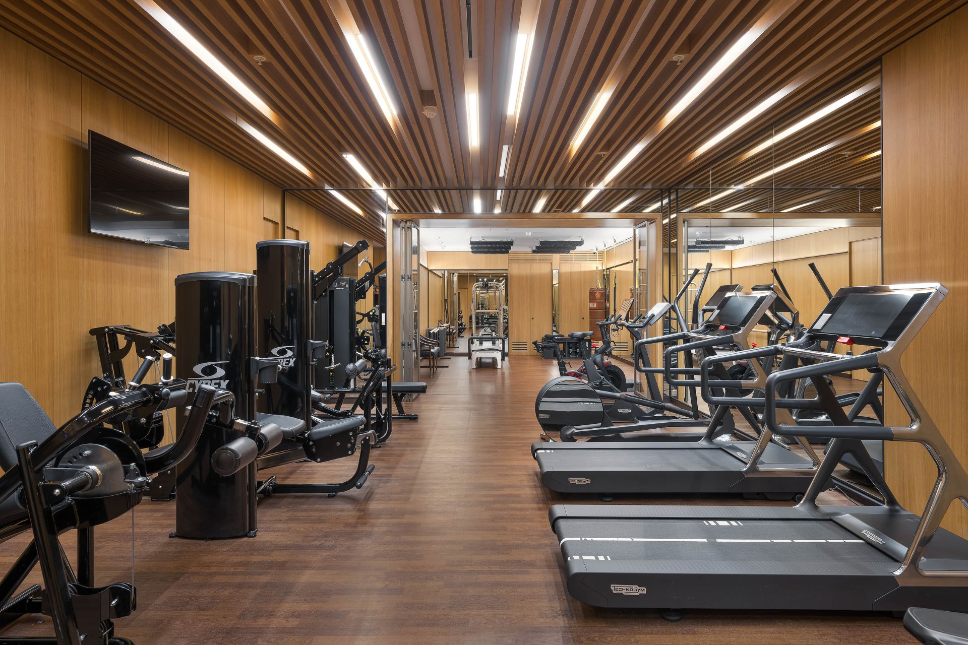 Gym with wood-panelled ceiling and black fitness machines