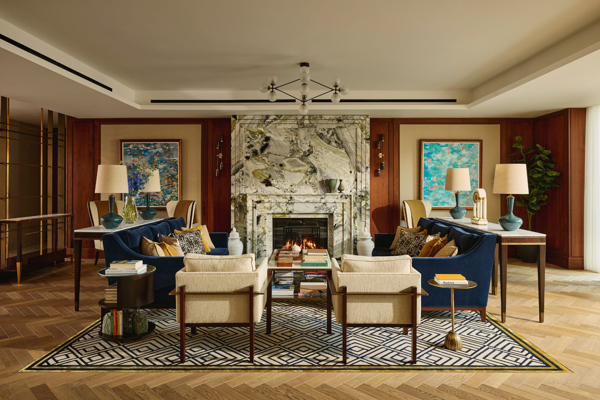 Lobby with deep blue velvet sofas, white armchairs and a white marble fireplace