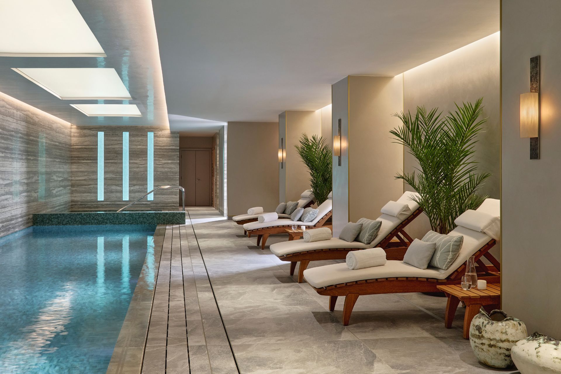 Indoor pool with marble columns and white sun loungers