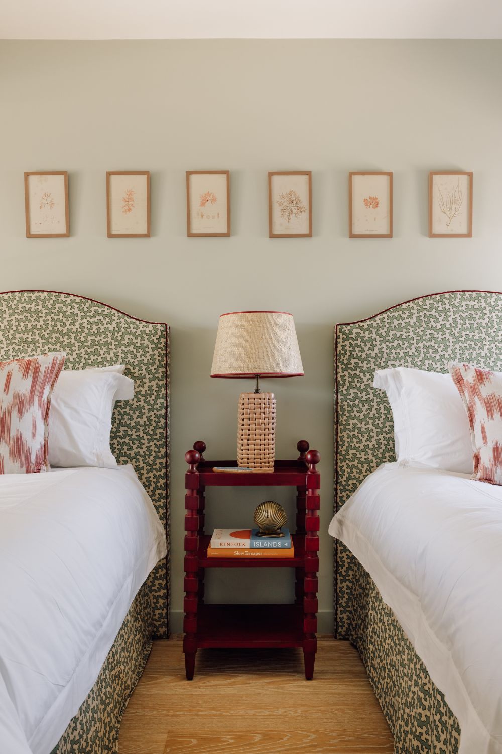 Kids' bedroom with green and white patterned headboards, pink and white patterned cushions, and white bedding