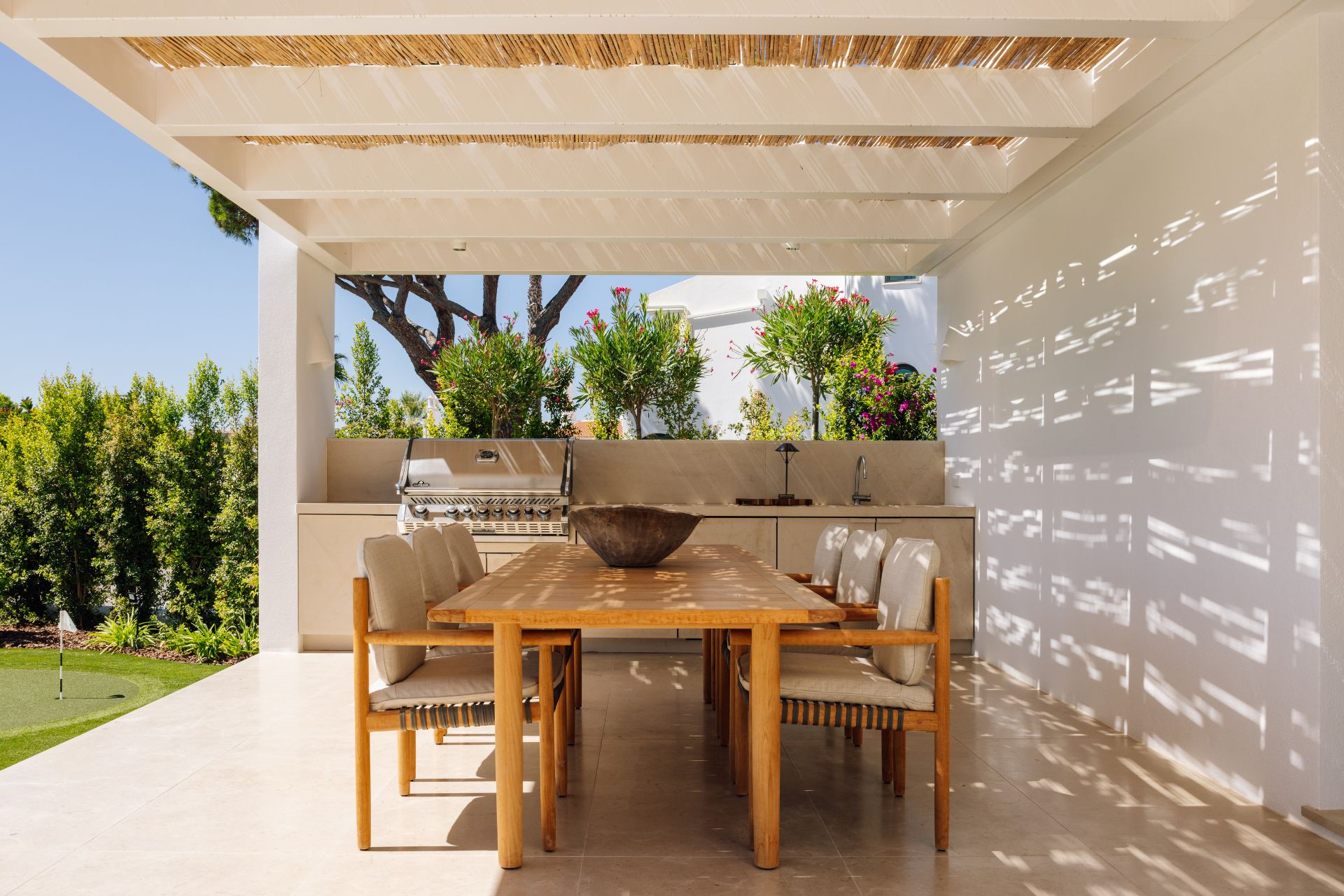 Outdoor kitchen in Portuguese villa with rattan chairs and an oak table