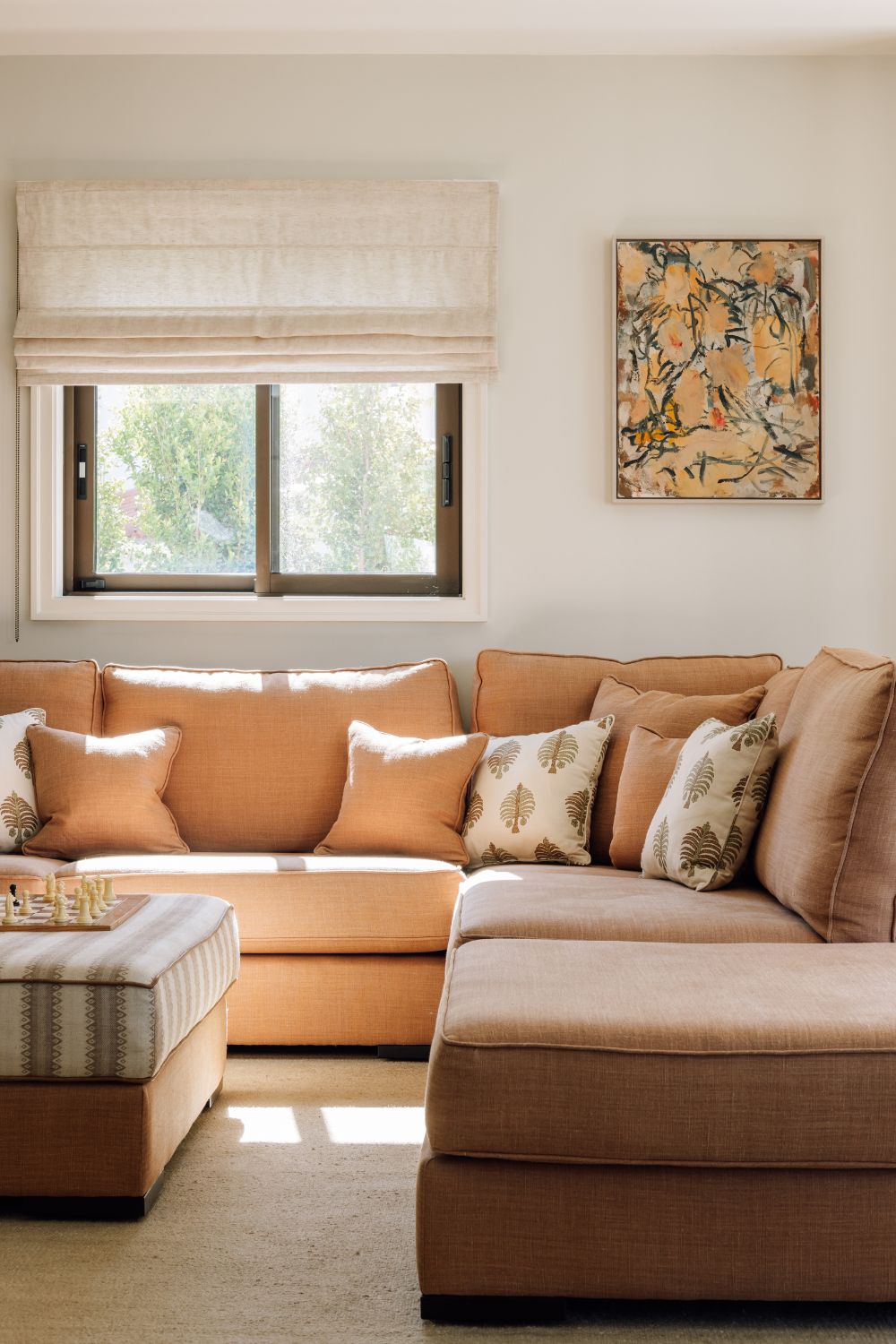 Living room with pale pink sofa, white blinds and white patterned cushions