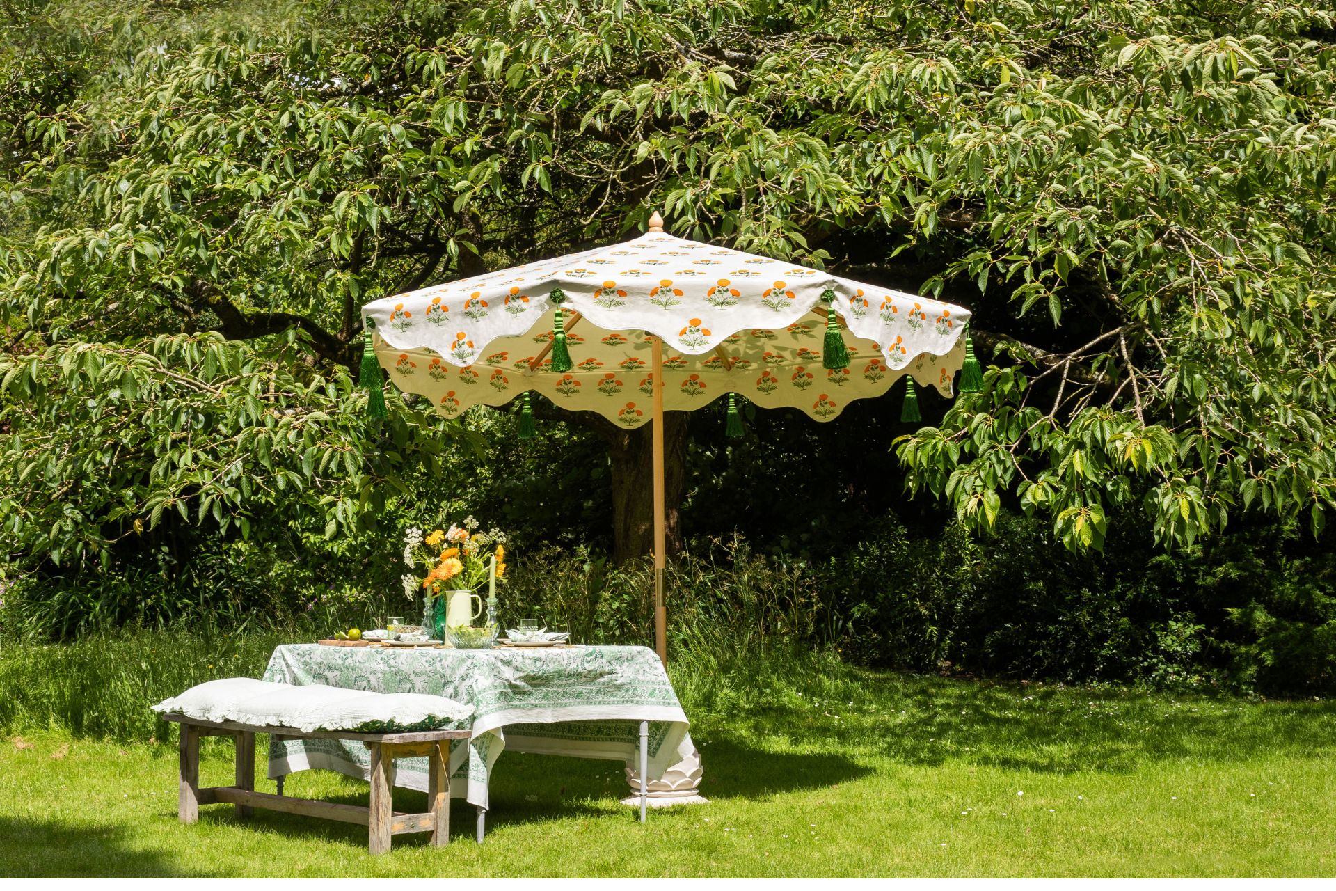Lawned garden with white and orange patterned parasol and table with green and white tablecloth