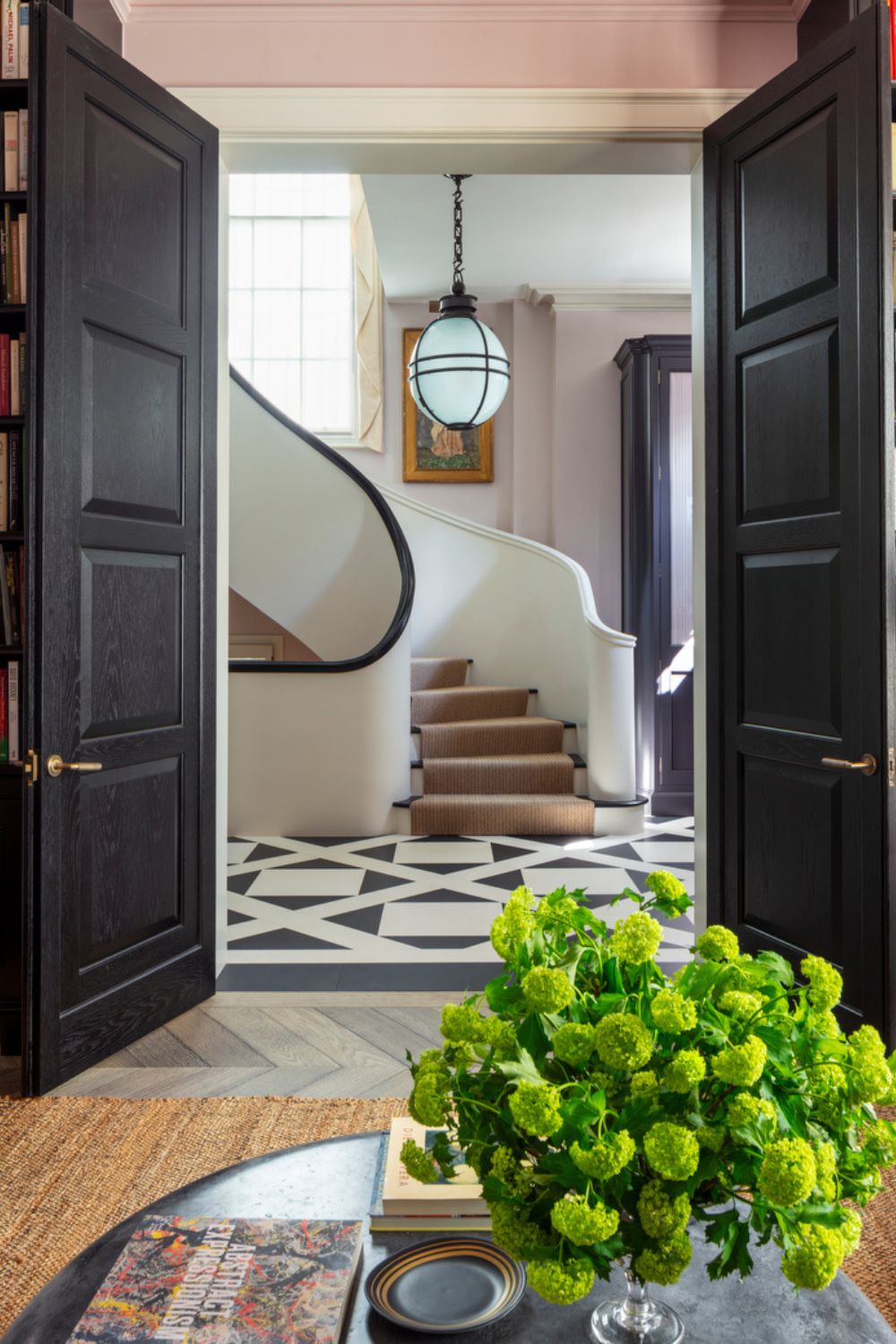 Hallway with curved staircase, checkerboard flooring and black doors