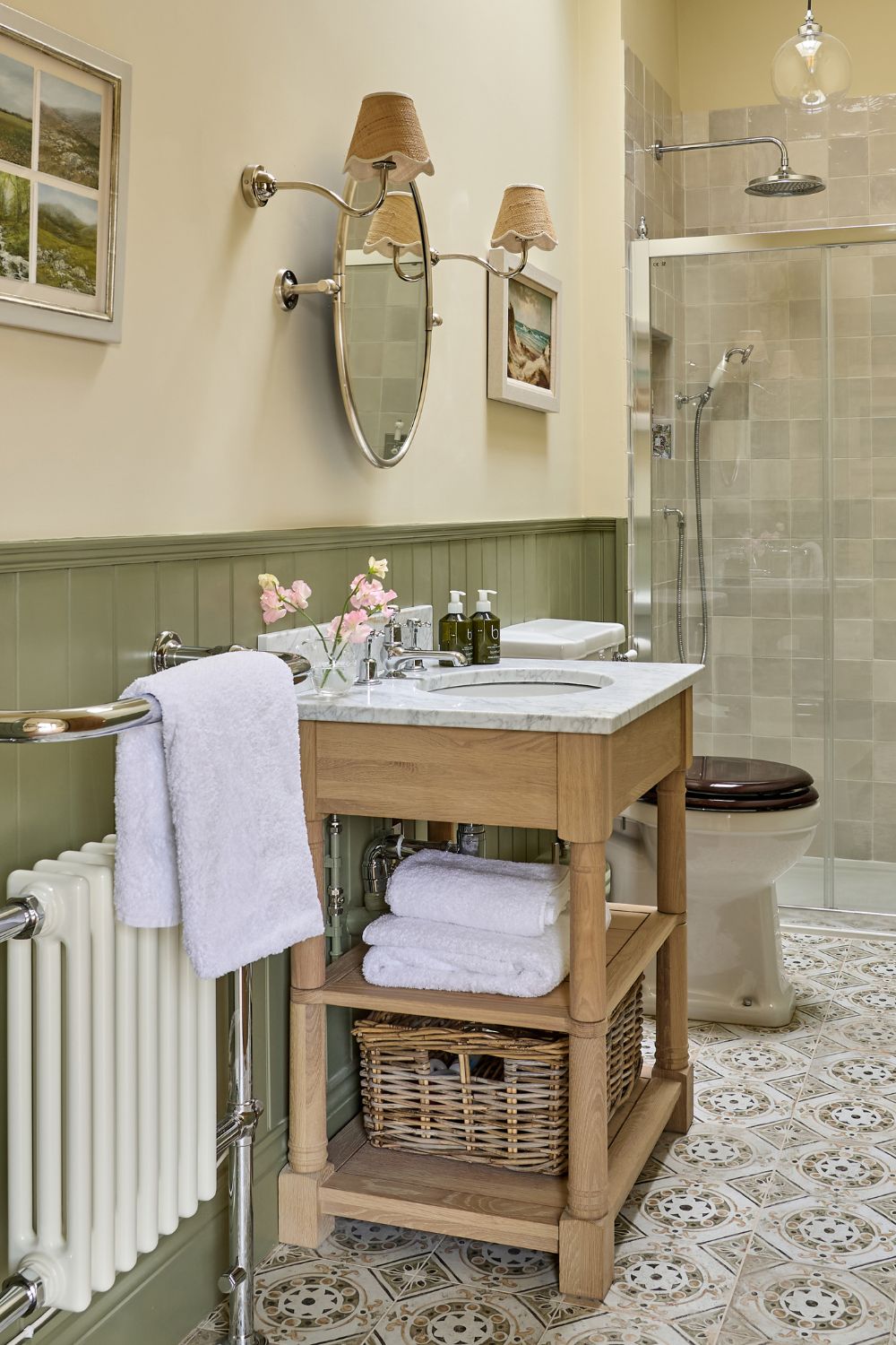 Bathroom with sage green panelling, blue and white floor tiles, and a wooden vanity unit with a white marble top