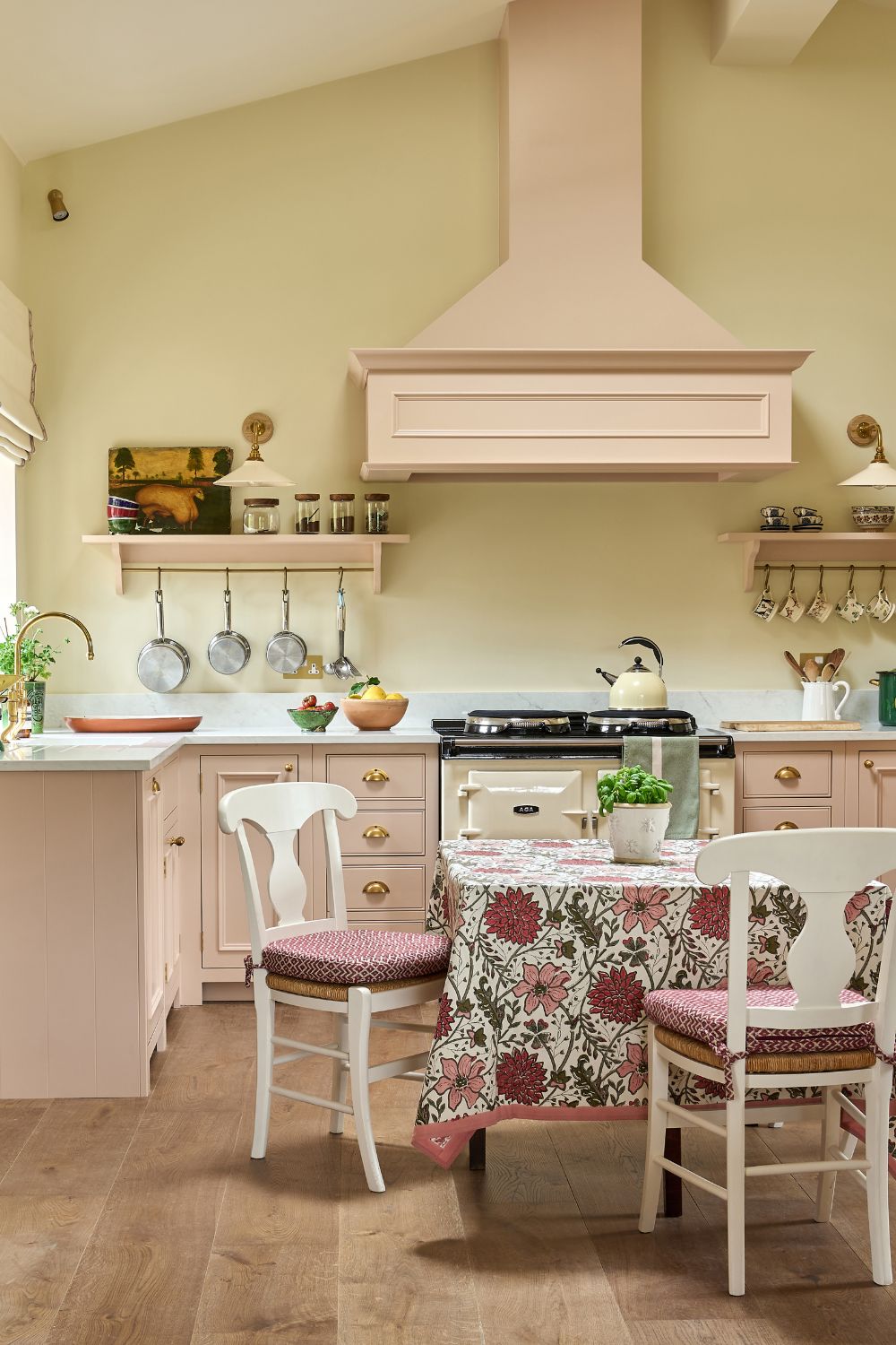 Cream kitchen with pale pink cupboards, matching extractor fan, and white marble worktops