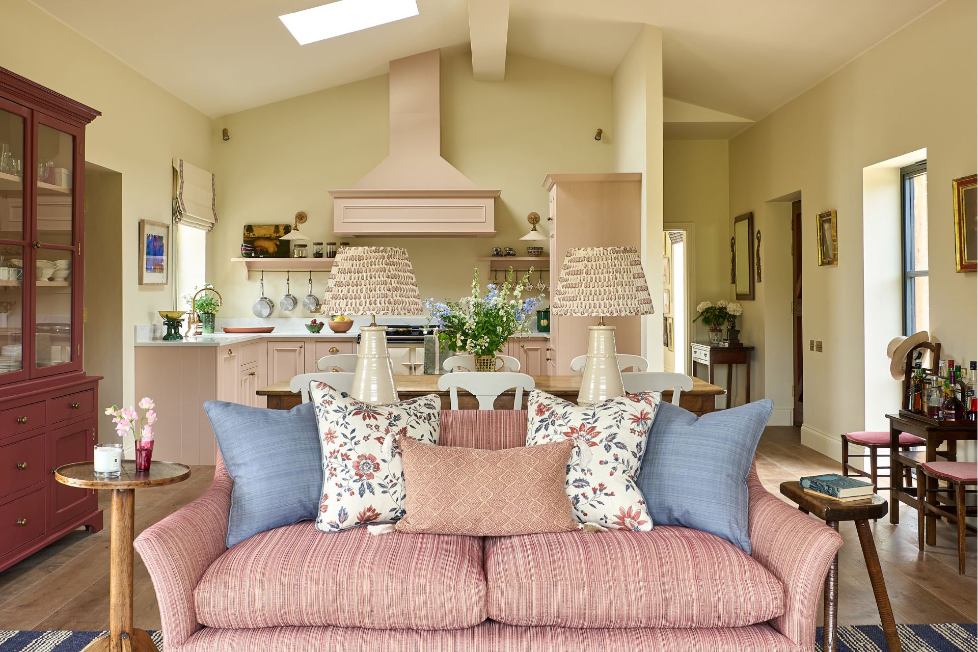 Living room with pale pink textured sofa, pale blue cushions and a plum-coloured dresser