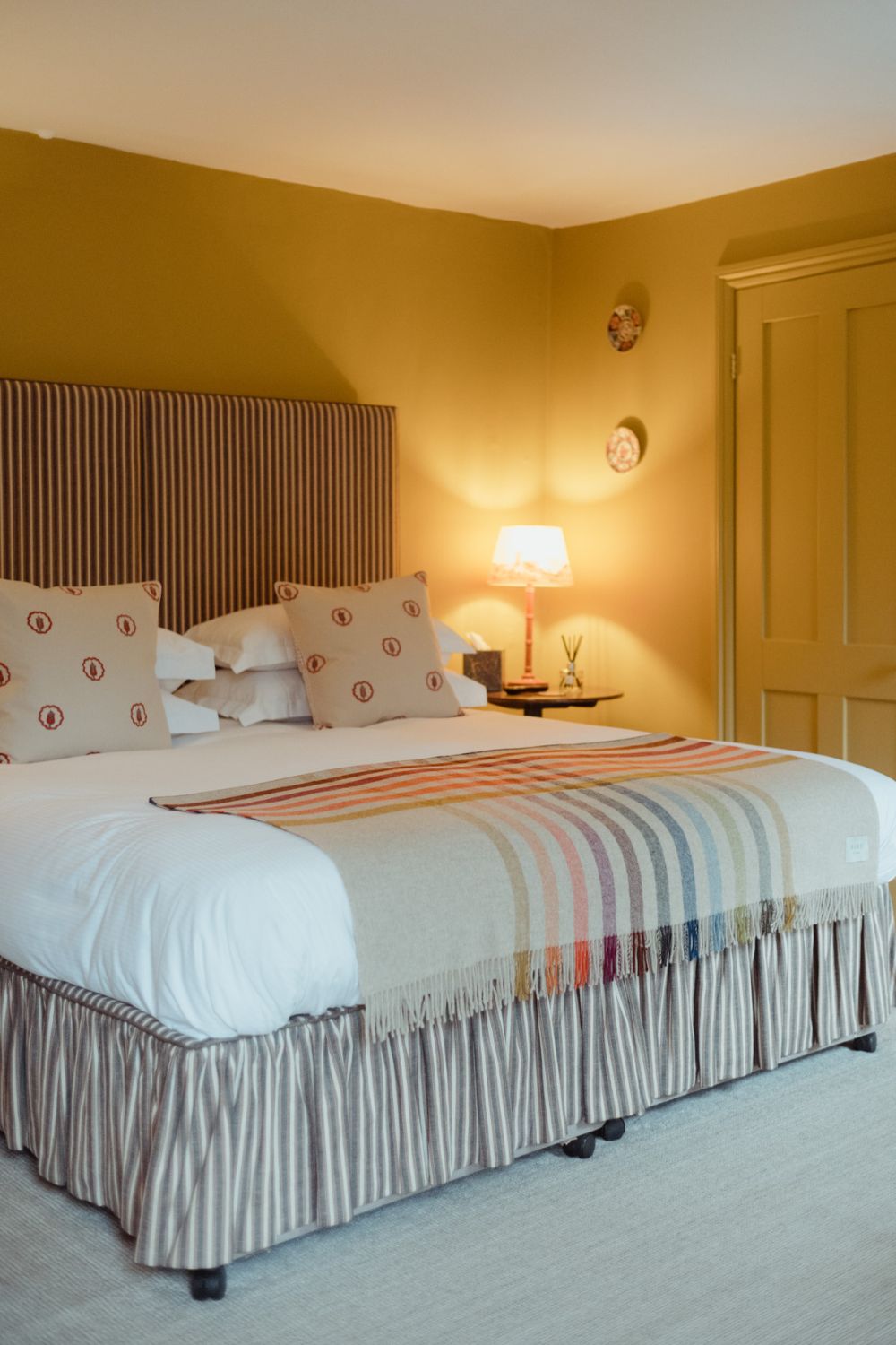 Yellow hotel bedroom with white bed linen and a pale orange and cream throw