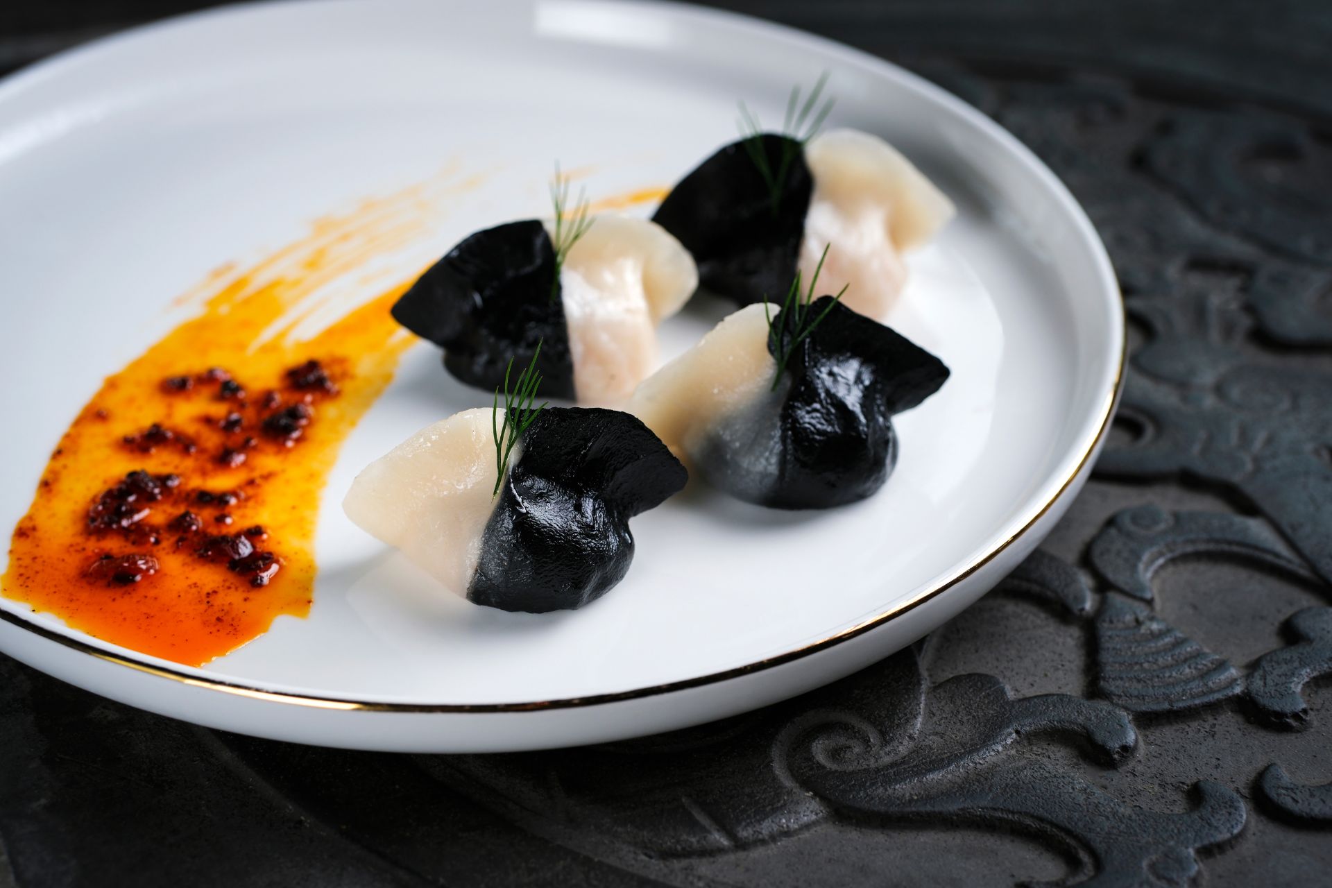 BLack and white dumplings with an orange jus