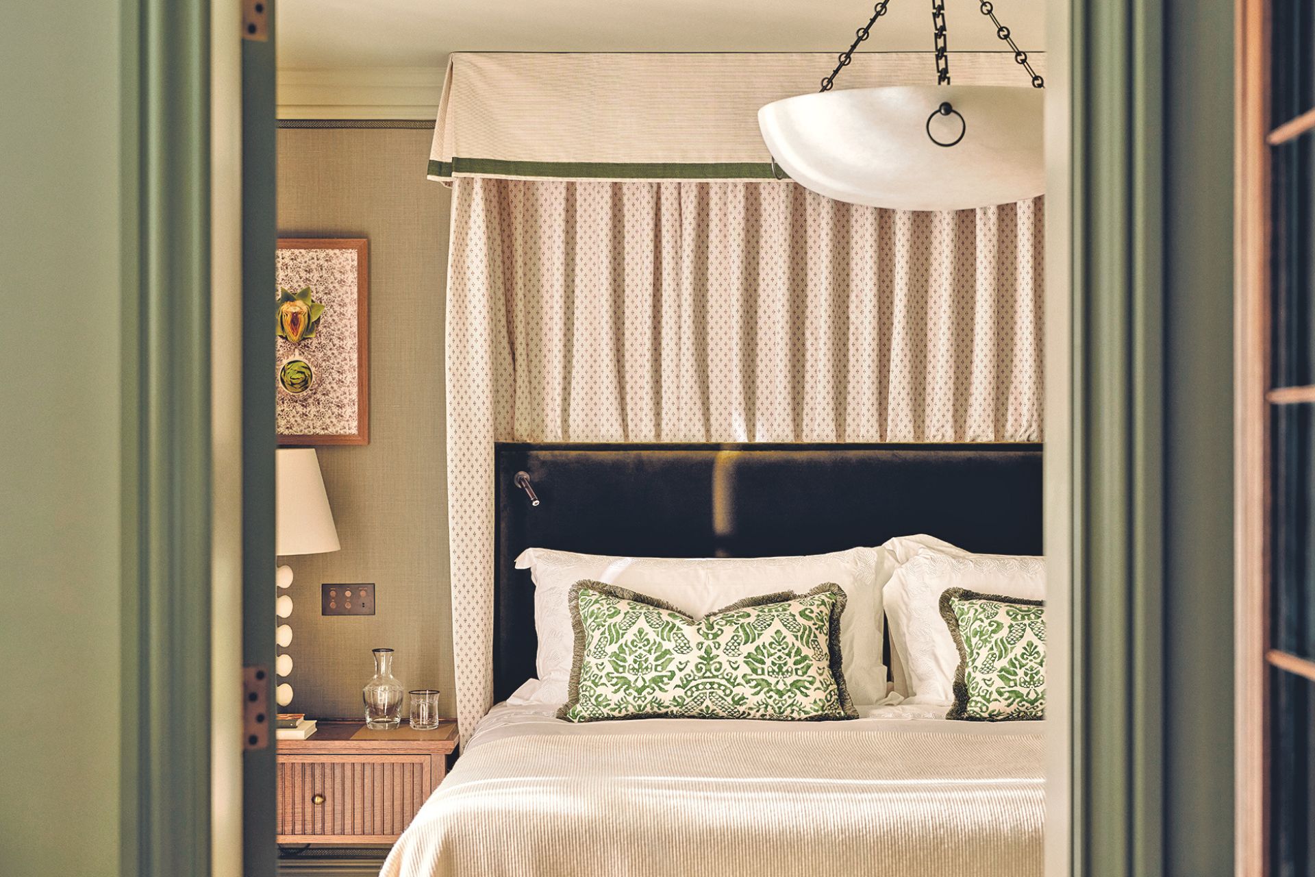 Hotel room with sage green walls and a cream four poster bed